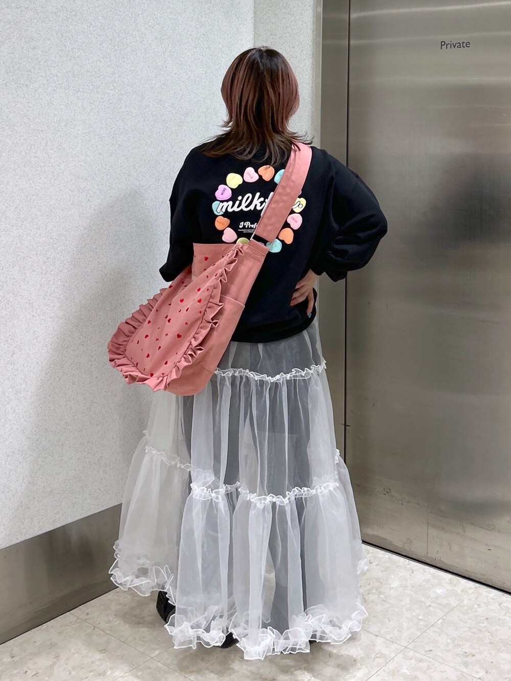 ブラック系のスウェット、ピンク系のショルダーバッグ、ブラック系のブーツを着用したレディースの春コーディネートの3枚目の写真