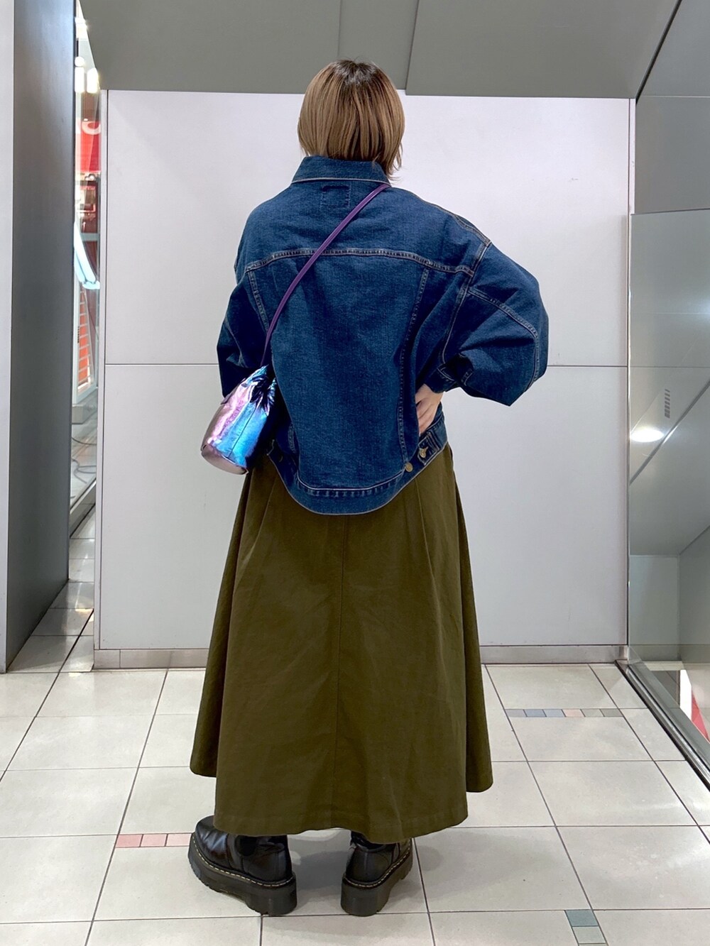 グリーン系のジャンパースカート、ブラック系のブーツ、ブルー系のデニムジャケットを着用したレディースの冬コーディネートの3枚目の写真