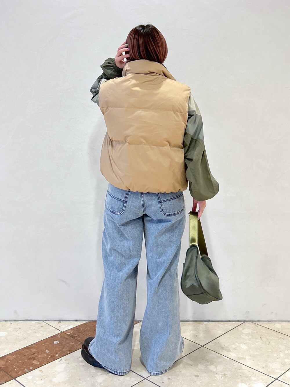 ブルー系のデニムパンツ、グリーン系のハンドバッグ、ブラック系のブーツを着用したレディースの冬コーディネートの4枚目の写真