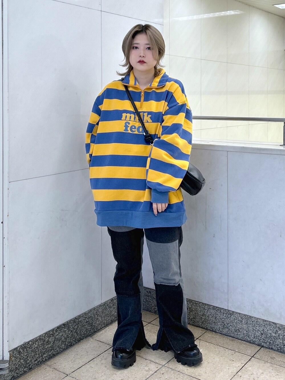 イエロー系のスウェット、ブラック系のデニムパンツ、ブラック系のショルダーバッグを着用したレディースの冬コーディネートの2枚目の写真