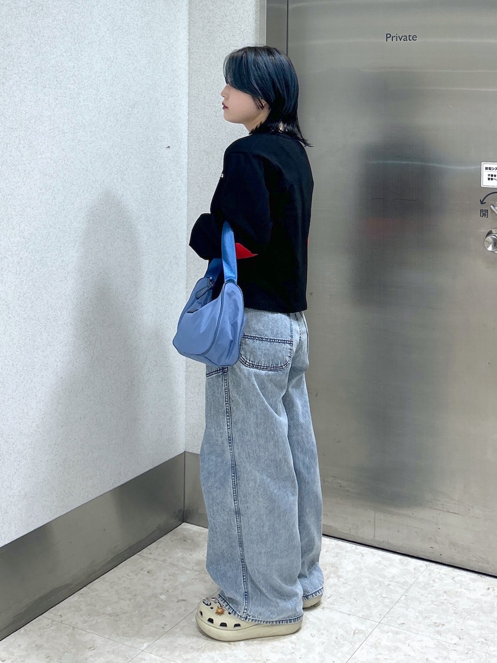 ブルー系のハンドバッグ、ブルー系のデニムパンツ、ベージュ系のサンダルを着用したレディースの夏コーディネートの4枚目の写真