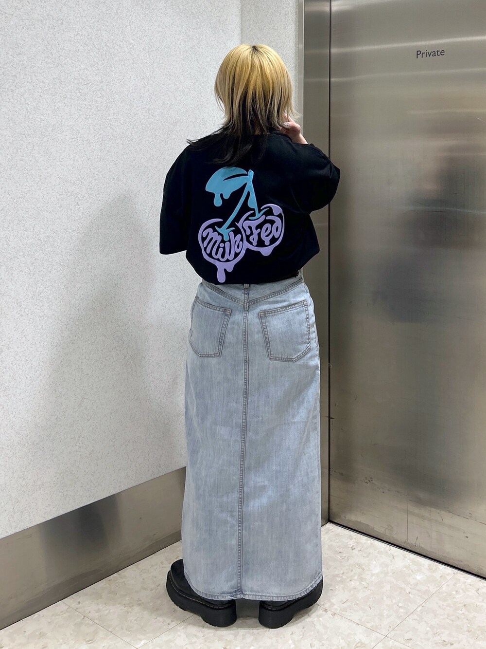 ブラック系のTシャツ/カットソー、ブルー系のデニムスカート、ブルー系のハンドバッグを着用したレディースの春コーディネートの2枚目の写真