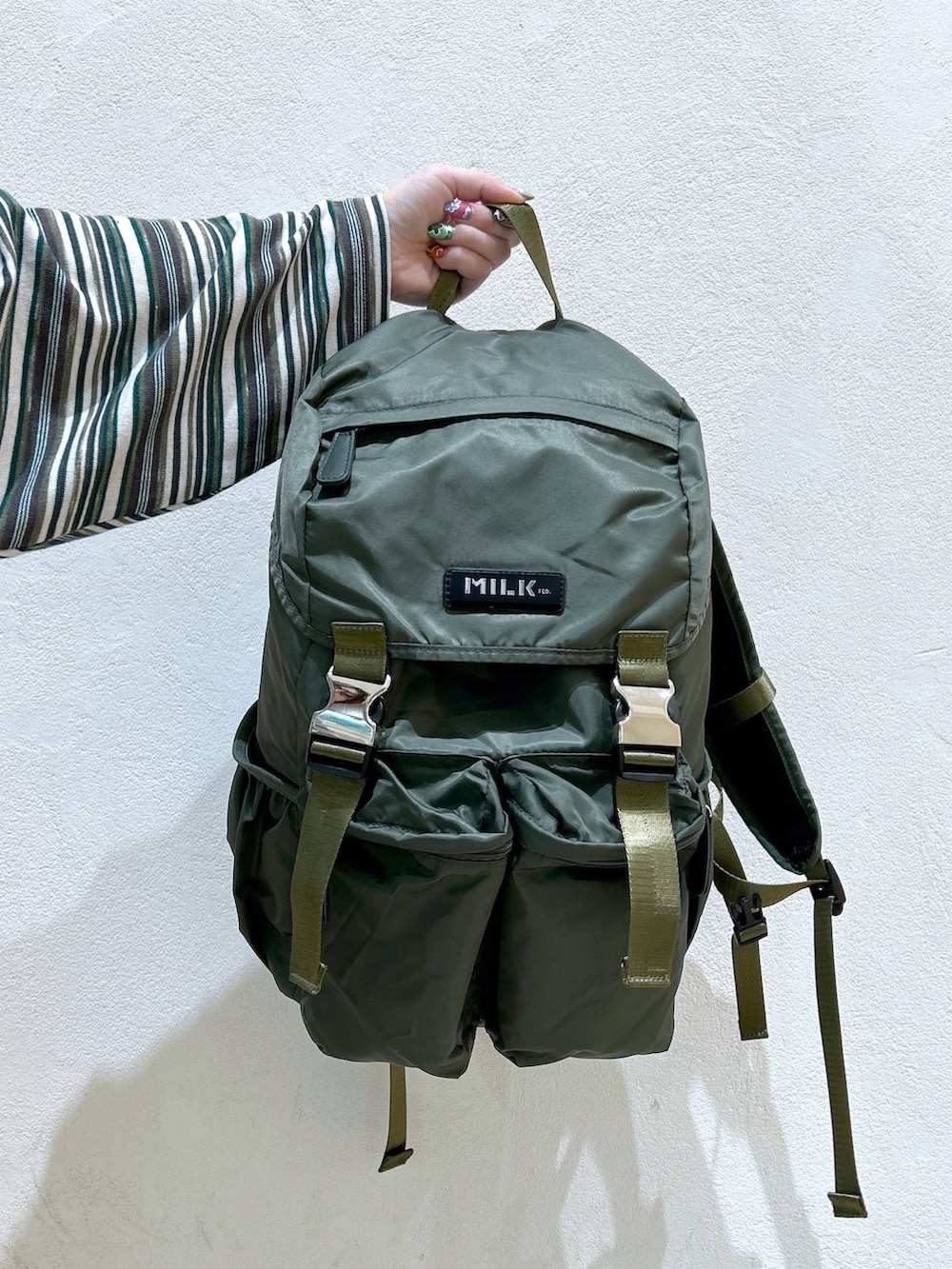 グリーン系のポロシャツ、ベージュ系のスウェットパンツ、グリーン系のバックパック/リュックを着用したレディースの冬コーディネートの7枚目の写真