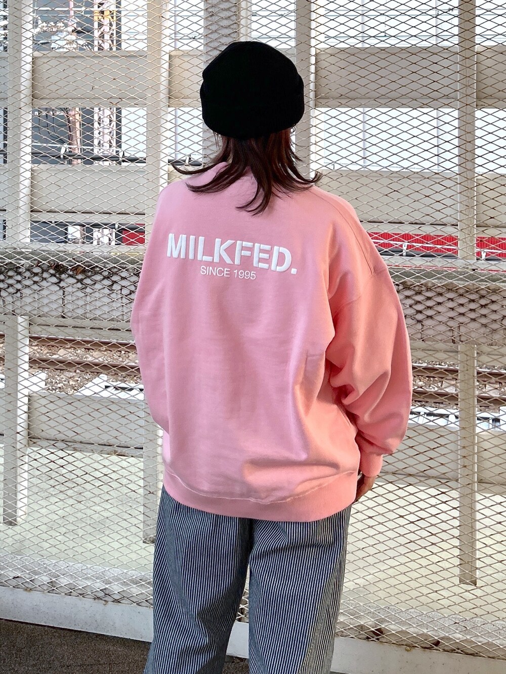 ピンク系のスウェット、ブラック系のショルダーバッグ、ブラック系のブーツを着用したレディースの冬コーディネートの5枚目の写真