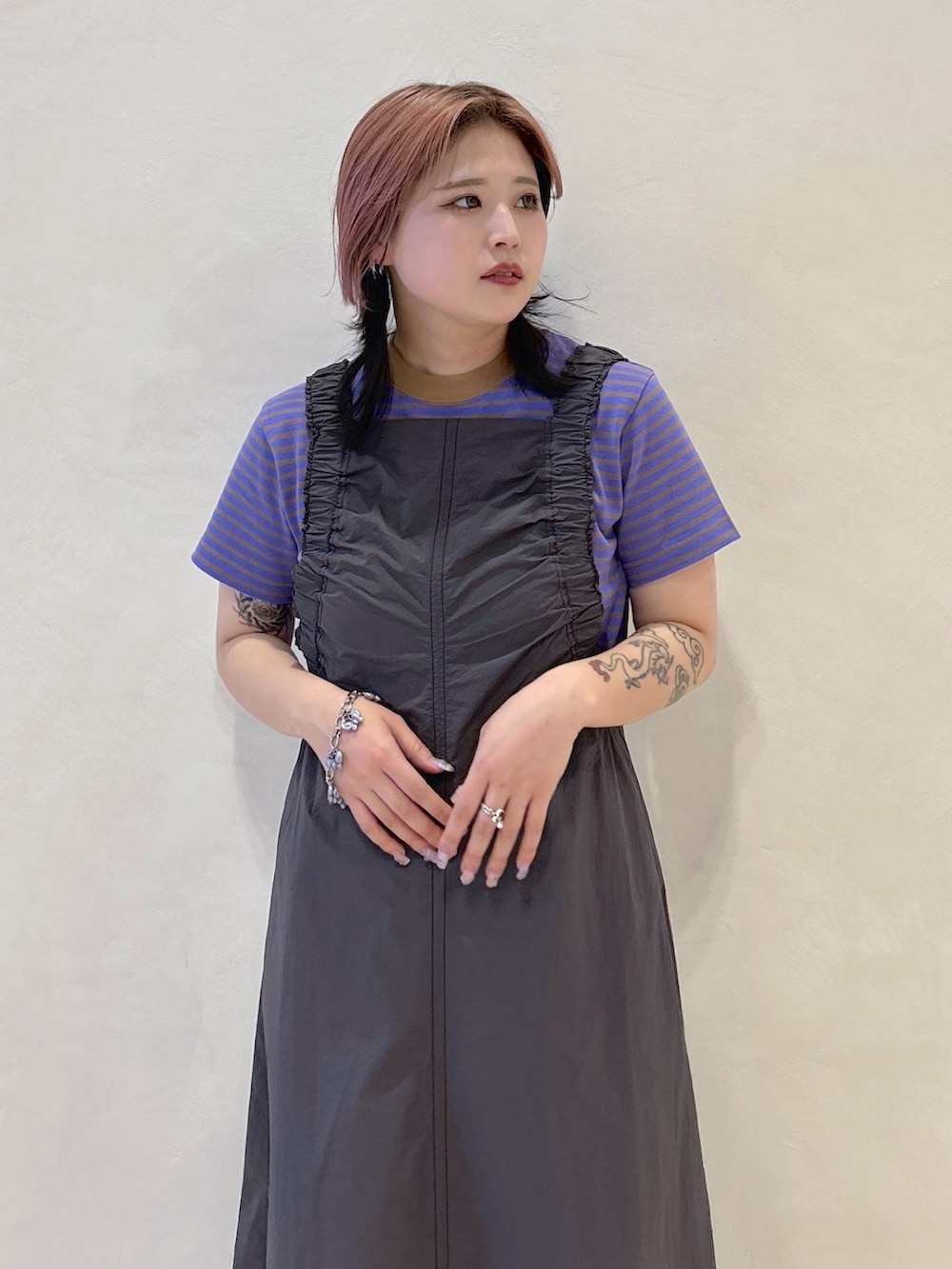 パープル系のTシャツ/カットソー、グレー系のワンピース、ブラック系のショルダーバッグを着用したレディースの春コーディネートの5枚目の写真