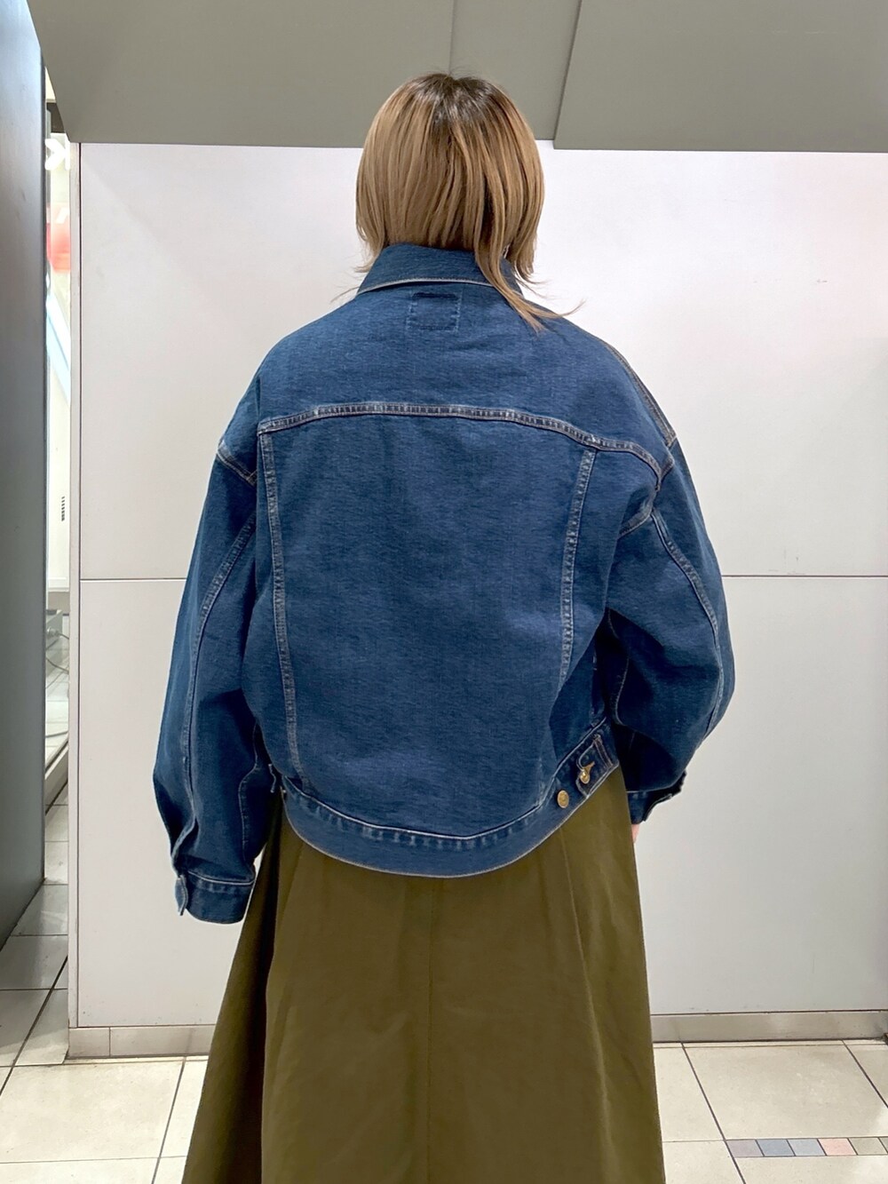 グリーン系のジャンパースカート、ブラック系のブーツ、ブルー系のデニムジャケットを着用したレディースの冬コーディネートの6枚目の写真