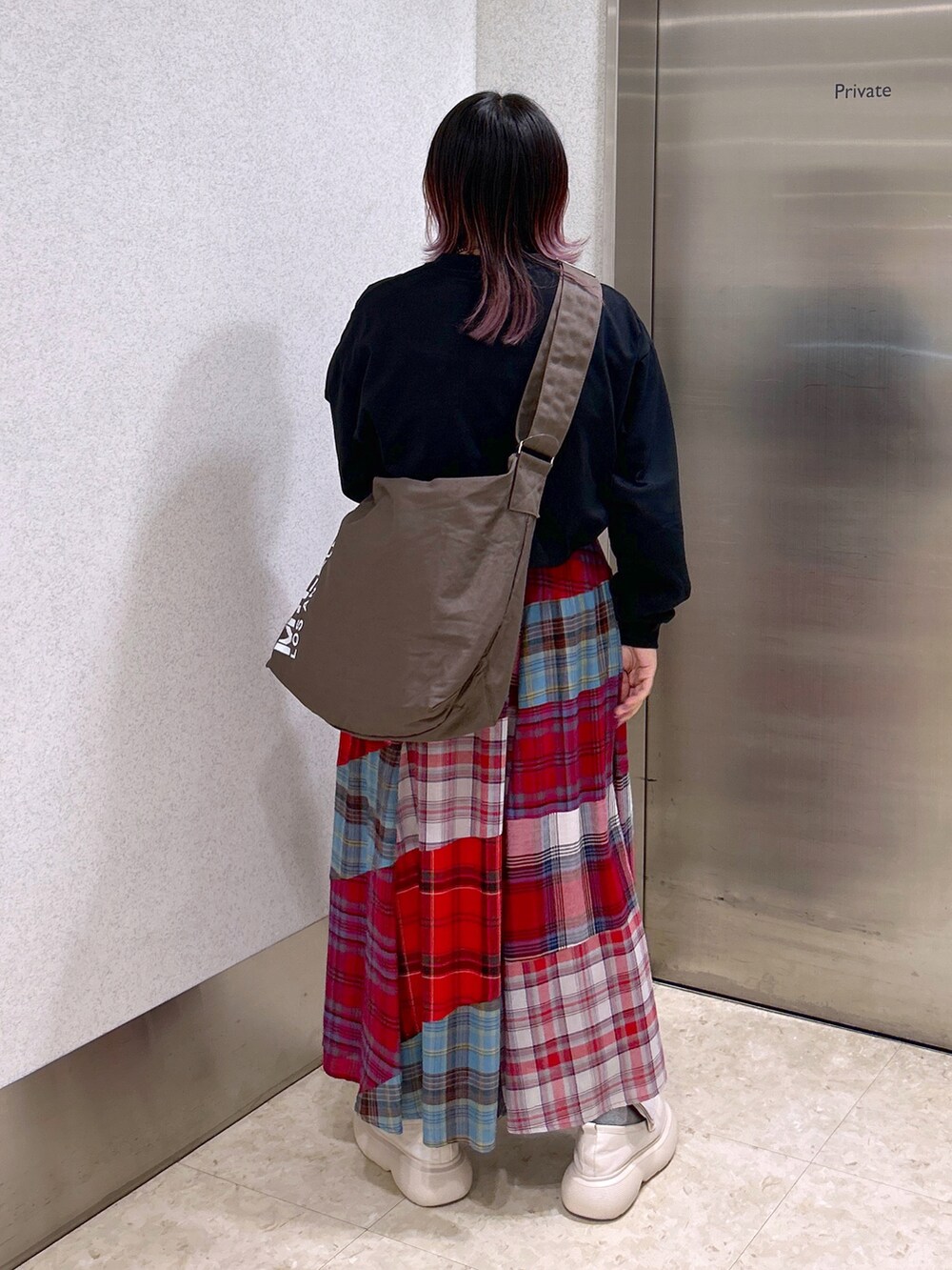 ブラック系のTシャツ/カットソー、ブラウン系のショルダーバッグ、レッド系のスカートを着用したレディースの秋コーディネートの2枚目の写真