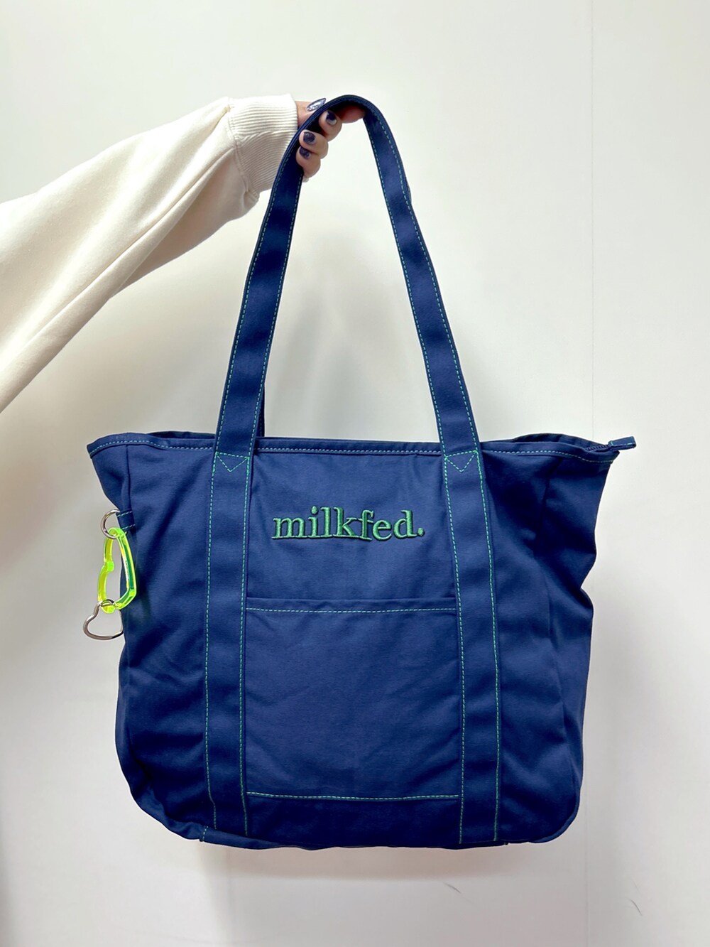 ホワイト系のスウェット、ブルー系のトートバッグ、ブルー系のデニムパンツを着用したレディースの秋コーディネートの4枚目の写真