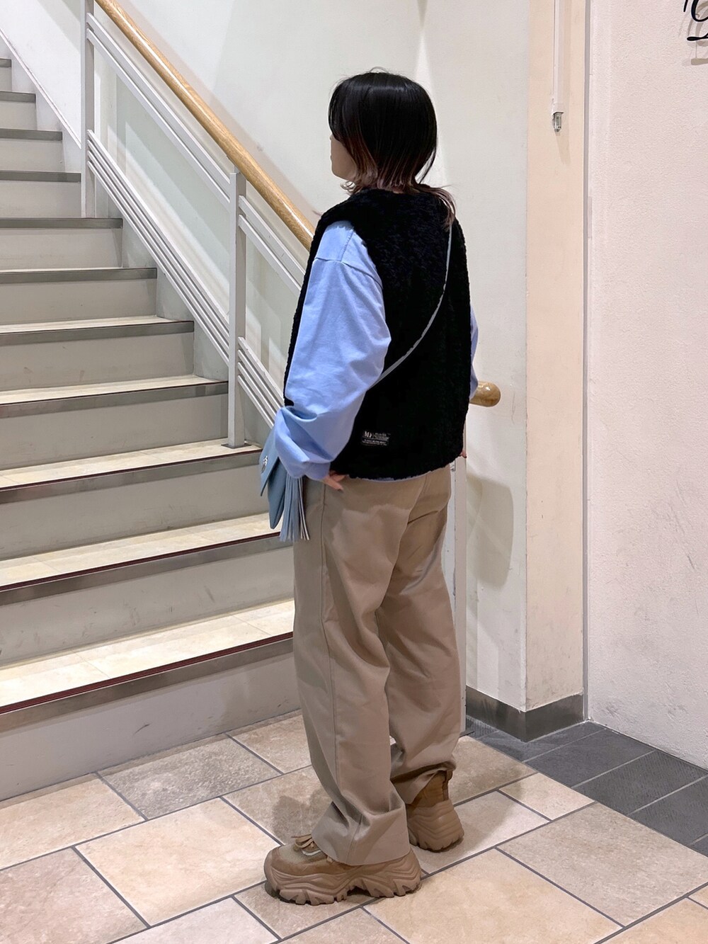 ブラック系のベスト、ブルー系のTシャツ/カットソー、ブルー系のショルダーバッグを着用したレディースの夏コーディネートの3枚目の写真