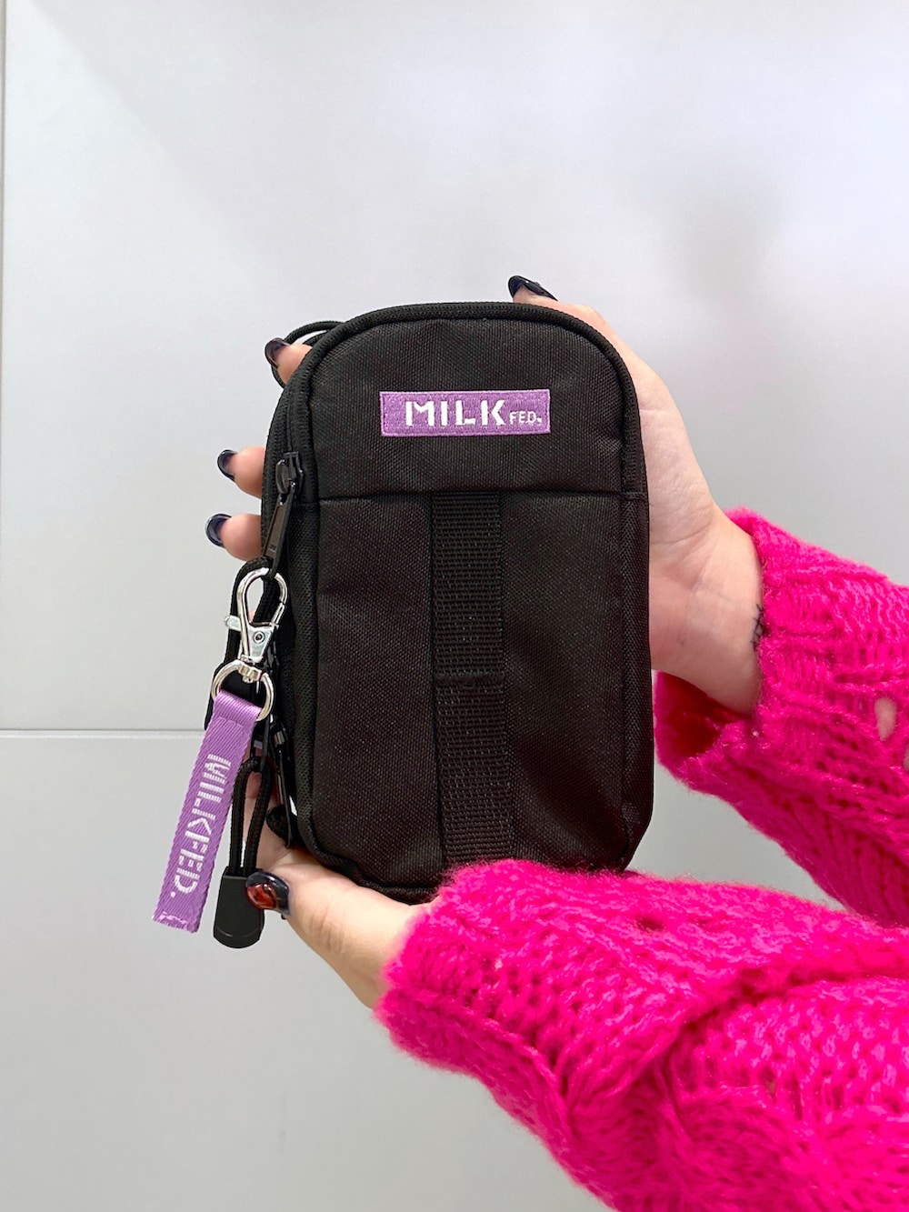 ピンク系のニット/セーター、ブラック系のサロペット/オーバーオール、パープル系のショルダーバッグを着用したレディースの秋コーディネートの4枚目の写真