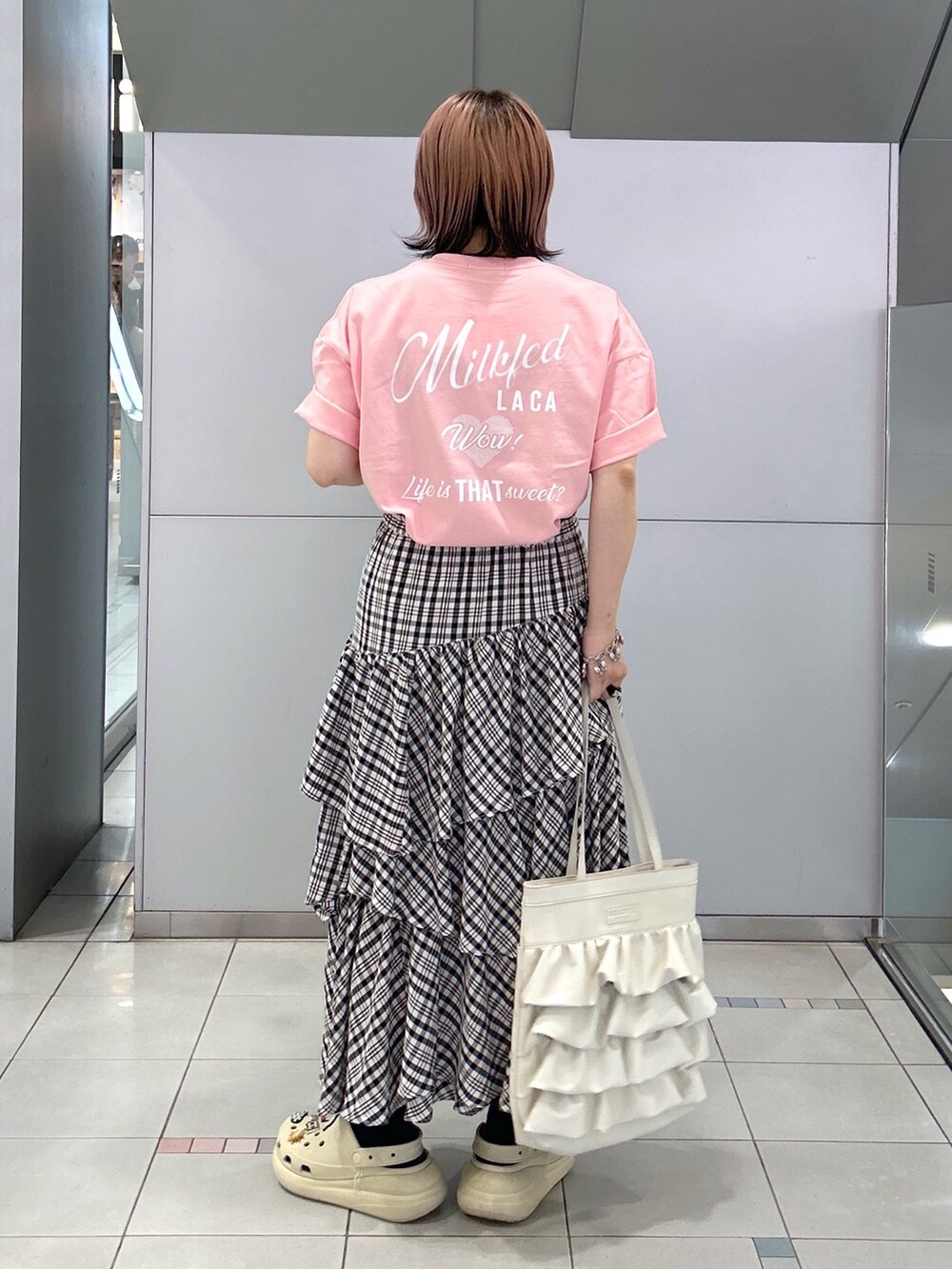 ピンク系のTシャツ/カットソー、ブラック系のスカート、ホワイト系のトートバッグを着用したレディースの夏コーディネートの2枚目の写真