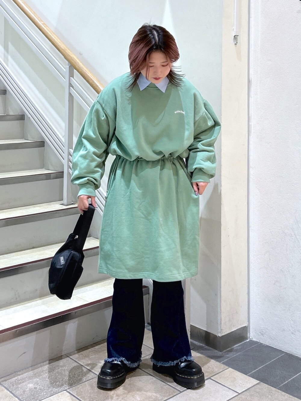 ブルー系のシャツ/ブラウス、グリーン系のワンピース、ブラック系のハンドバッグを着用したレディースの冬コーディネートの2枚目の写真