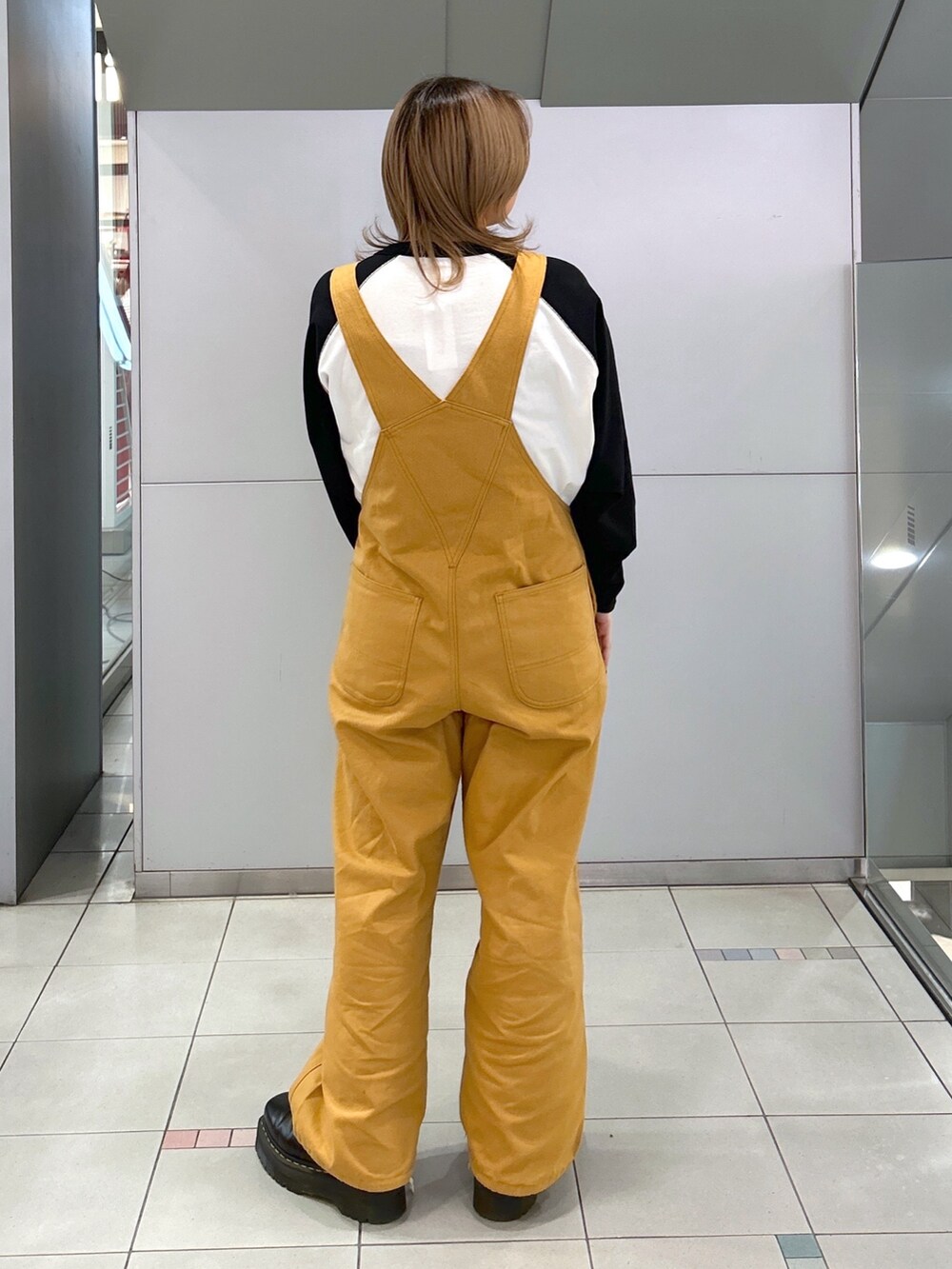 ブラック系のTシャツ/カットソー、ベージュ系のサロペット/オーバーオール、ブラック系のブーツを着用したレディースの冬コーディネートの4枚目の写真