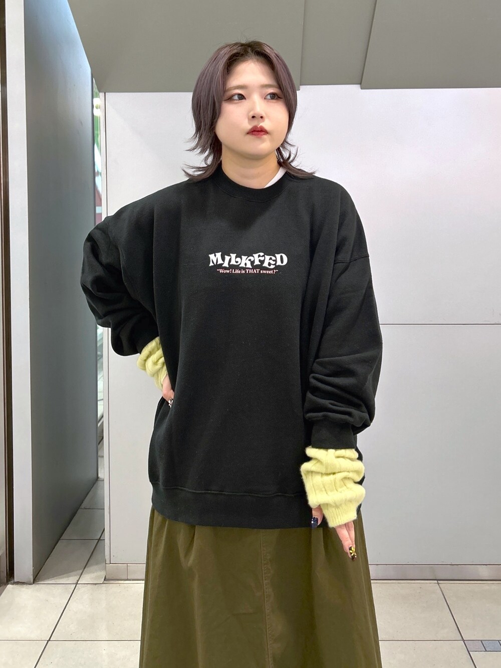 ブラック系のスウェット、グリーン系のジャンパースカート、シルバー系のショルダーバッグを着用したレディースの冬コーディネートの4枚目の写真