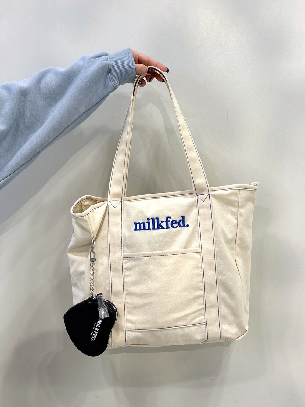 ブルー系のスウェット、ブルー系のトートバッグ、ブラック系のスカートを着用したレディースの秋コーディネートの4枚目の写真