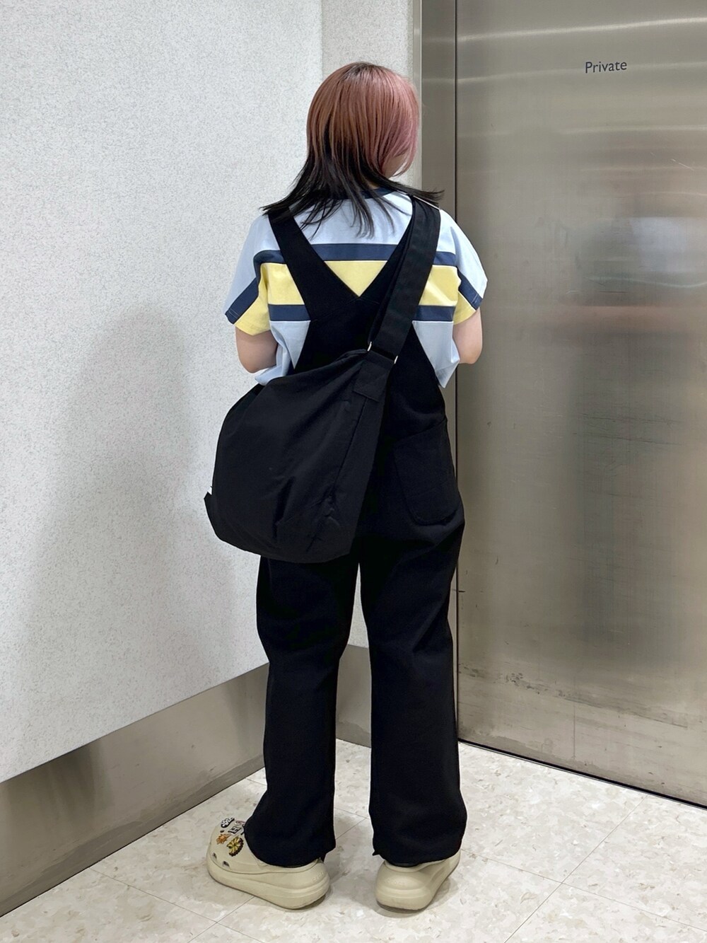 ブラック系のサロペット/オーバーオール、ブラック系のショルダーバッグ、ベージュ系のサンダルを着用したレディースの夏コーディネートの4枚目の写真