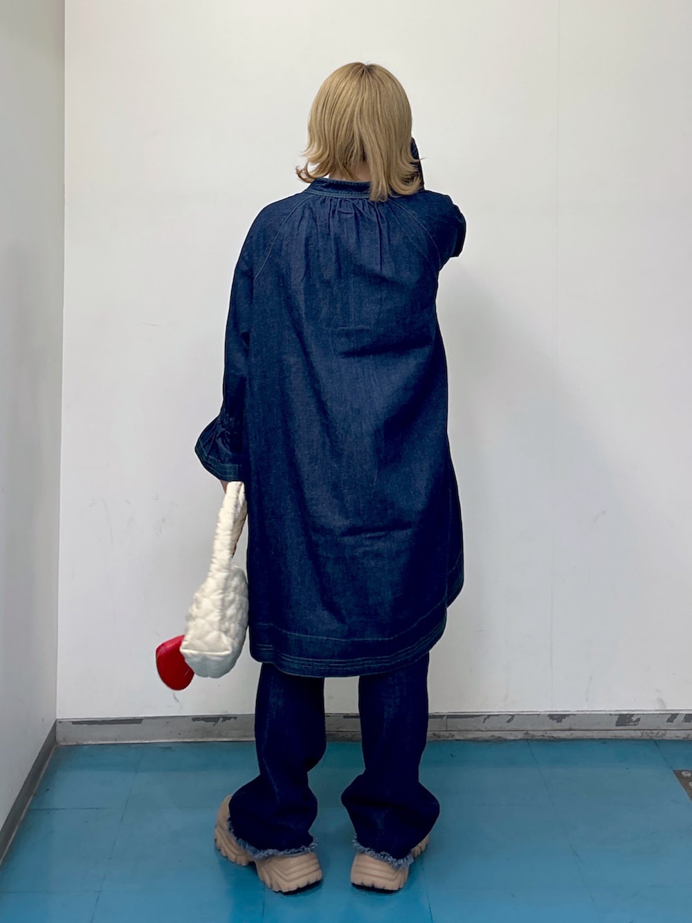 ブルー系のワンピース、ホワイト系のハンドバッグ、ブルー系のデニムパンツを着用したレディースの秋コーディネートの3枚目の写真