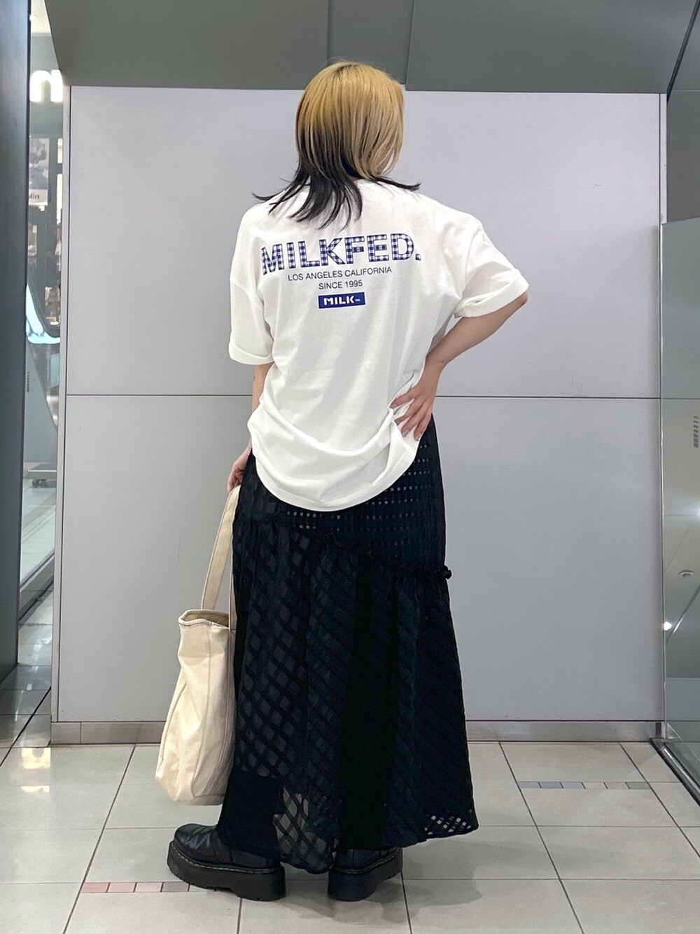 ホワイト系のTシャツ/カットソー、ブラック系のスカート、ブルー系のトートバッグを着用したレディースの春コーディネートの2枚目の写真