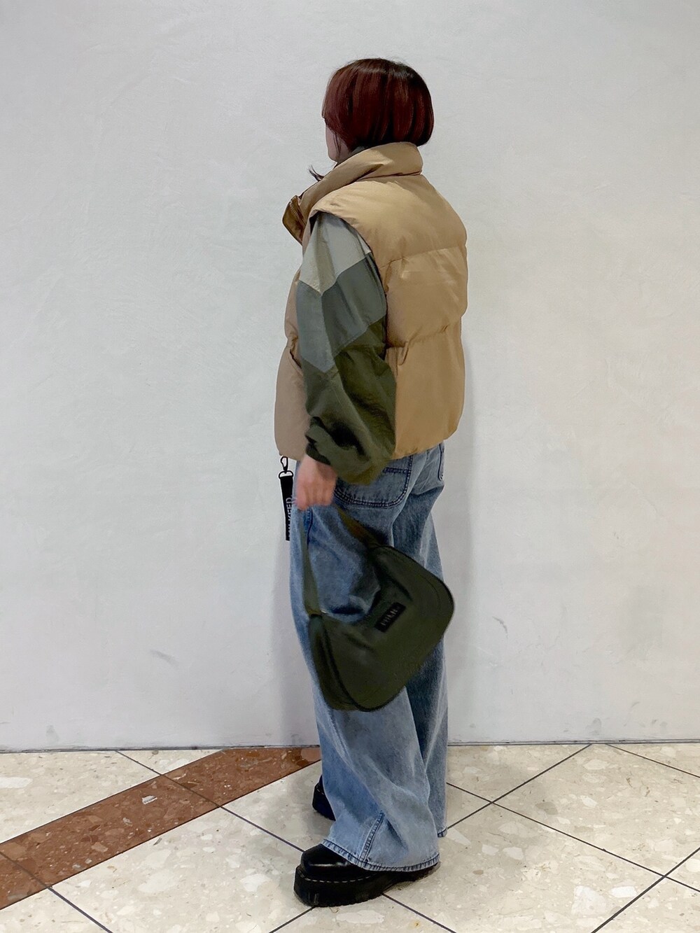 ブルー系のデニムパンツ、グリーン系のハンドバッグ、ブラック系のブーツを着用したレディースの冬コーディネートの3枚目の写真