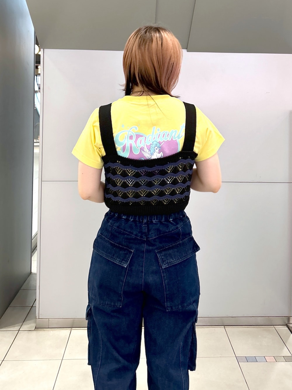 イエロー系のTシャツ/カットソー、ブラック系のキャミソール、ブラック系のブーツを着用したレディースの夏コーディネートの6枚目の写真
