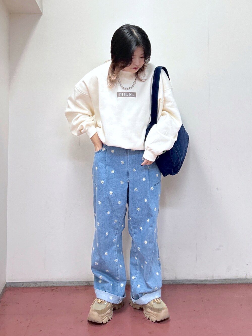 ホワイト系のスウェット、ブルー系のトートバッグ、ブルー系のデニムパンツを着用したレディースの秋コーディネートの2枚目の写真