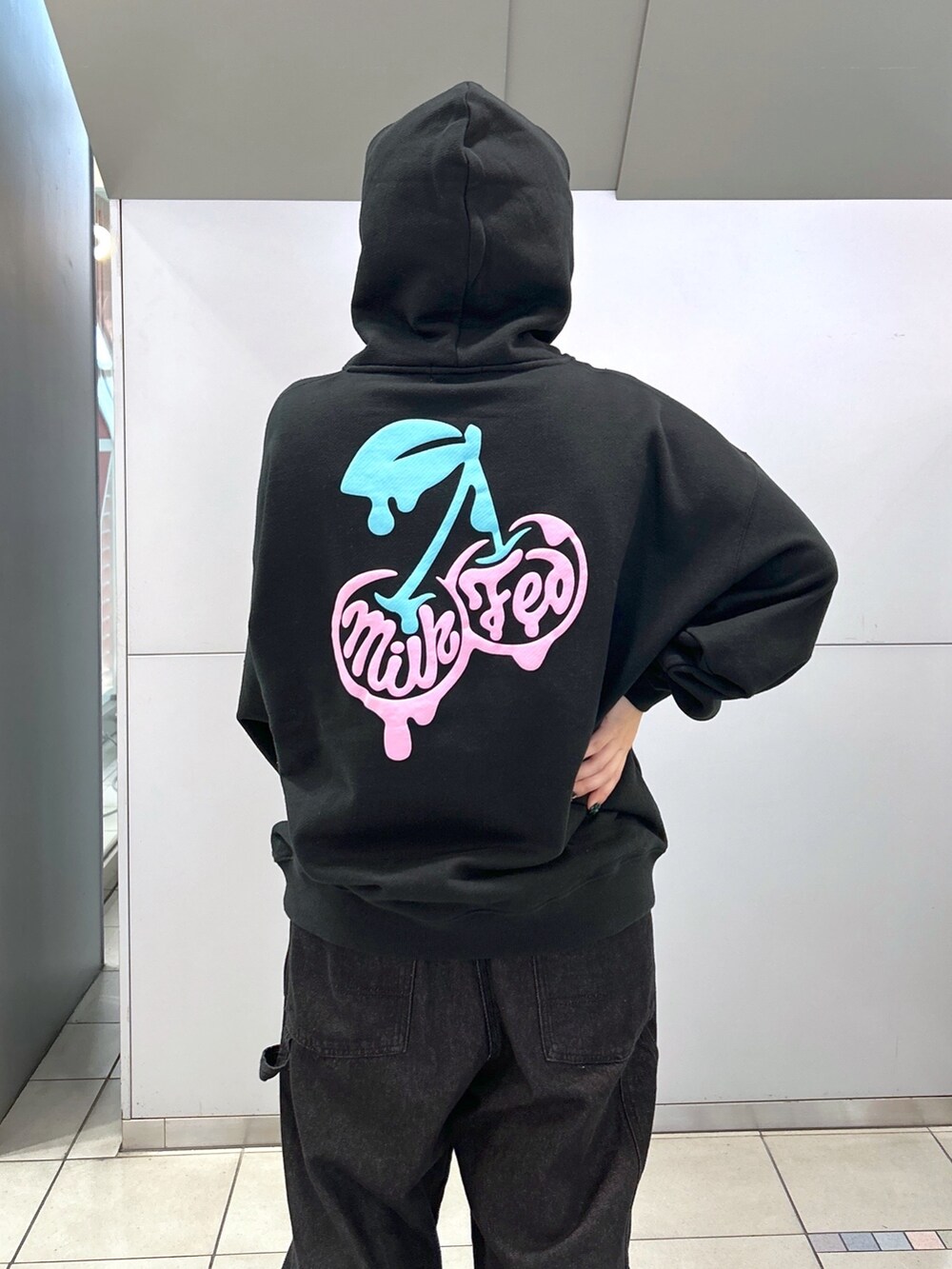 ブラック系のパーカー、ブラック系のサロペット/オーバーオール、ベージュ系のスニーカーを着用したレディースの秋コーディネートの5枚目の写真