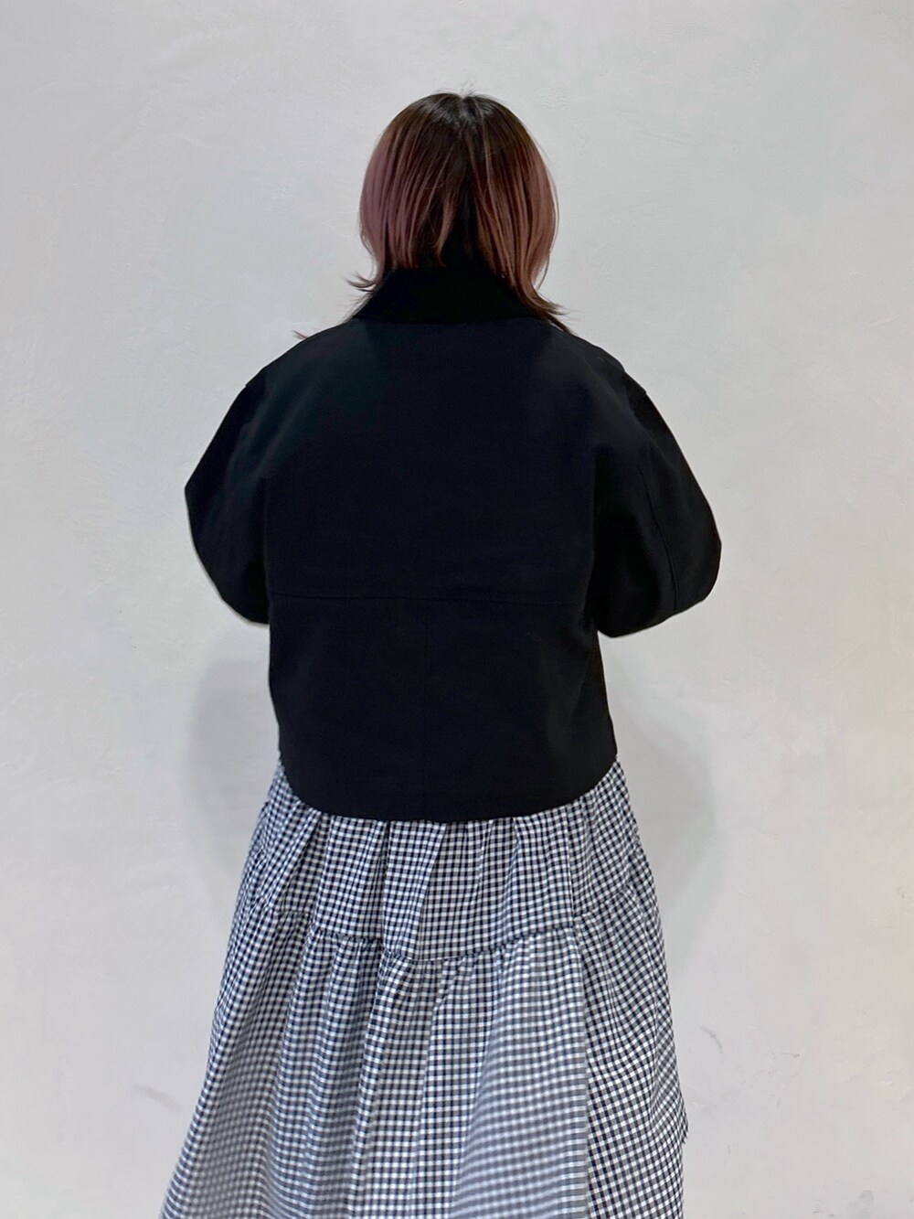 ブルー系のデニムパンツ、ブラック系のカバーオール、ブラック系のワンピースを着用したレディースの春コーディネートの2枚目の写真