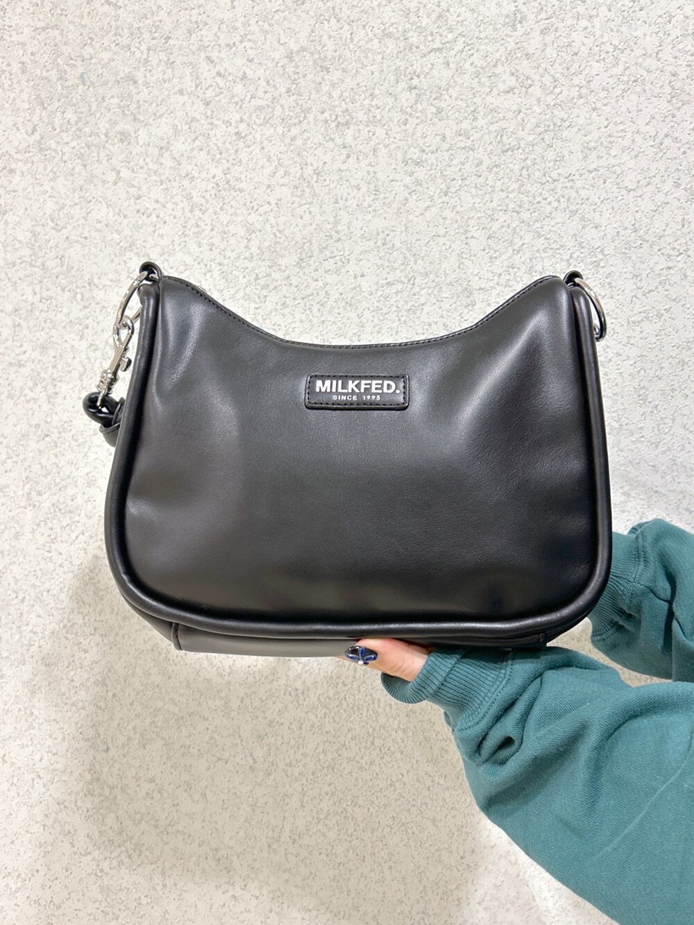 グリーン系のスウェット、ブラック系のショルダーバッグ、ブラック系のスカートを着用したレディースの冬コーディネートの5枚目の写真