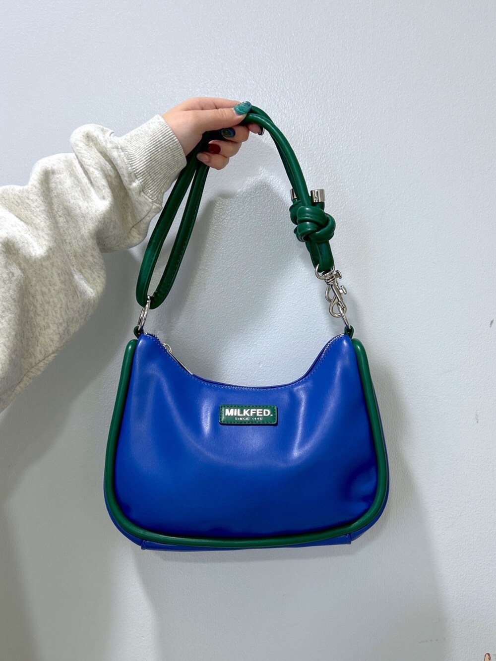 ブルー系のショルダーバッグ、ベージュ系のパーカー、グレー系のワンピースを着用したレディースの冬コーディネートの5枚目の写真