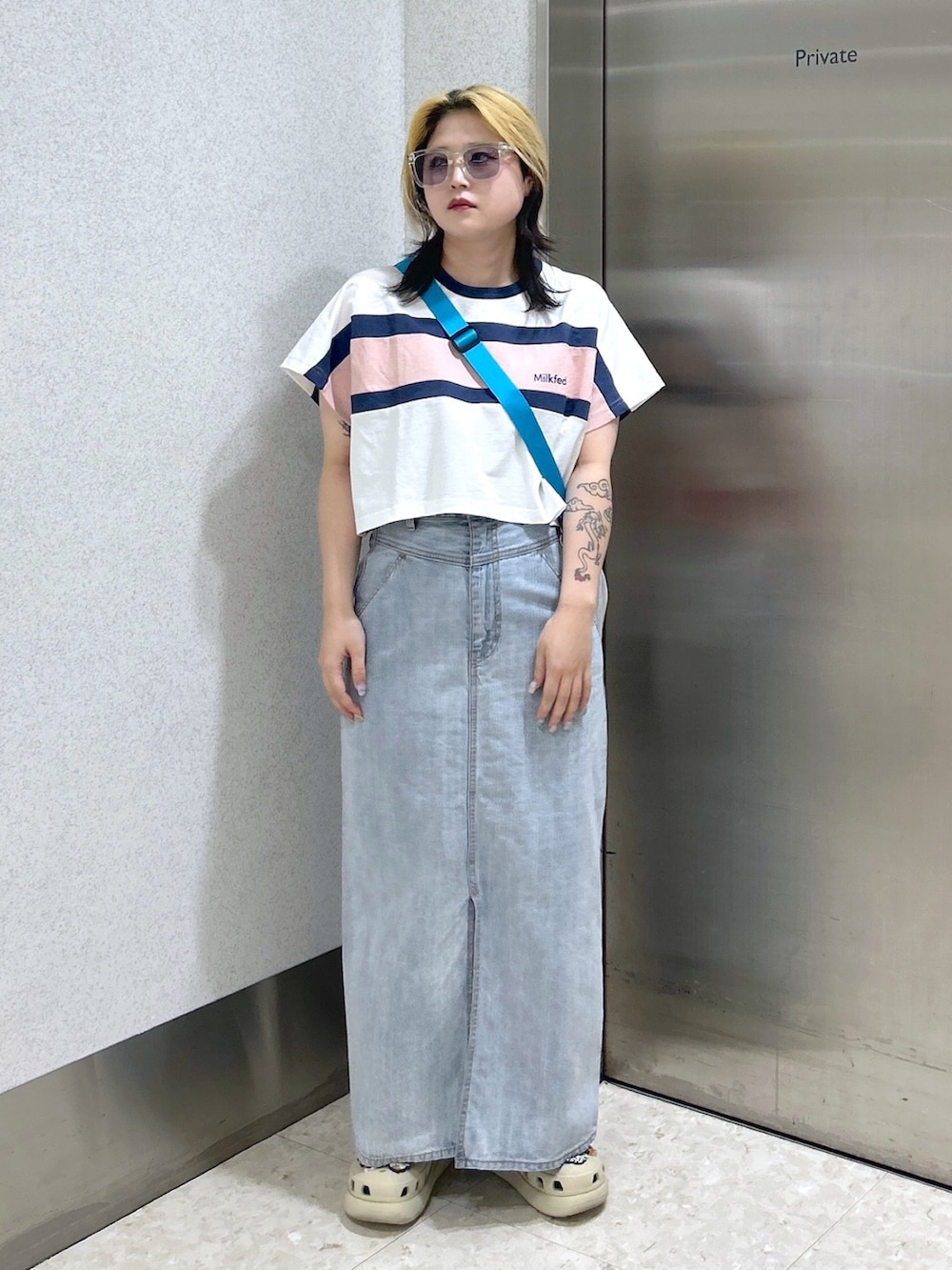 ホワイト系のTシャツ/カットソー、ブルー系のデニムスカート、ホワイト系のショルダーバッグを着用したレディースの春コーディネートの2枚目の写真