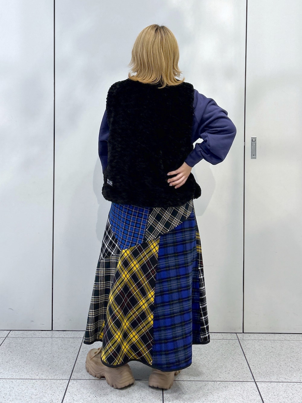 ブラック系のベスト、ブルー系のスウェット、ブラック系のスカートを着用したレディースの秋コーディネートの3枚目の写真