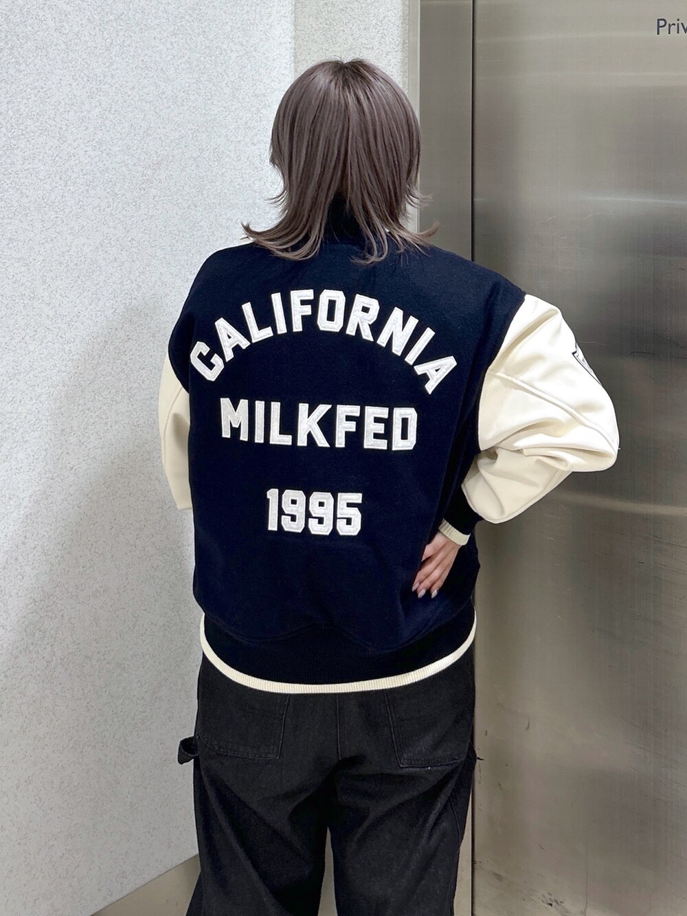 ブルー系のスタジャン、ブラック系のサロペット/オーバーオール、ベージュ系のスニーカーを着用したレディースの秋コーディネートの4枚目の写真