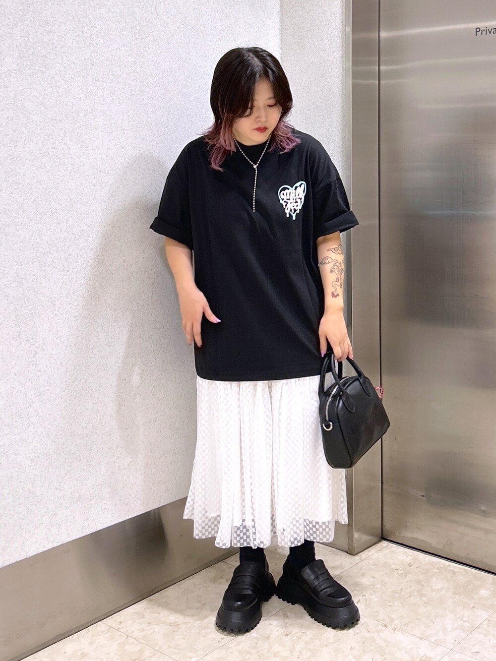 ブラック系のTシャツ/カットソー、ホワイト系のスカート、ブラック系のローファーを着用したレディースの夏コーディネートの3枚目の写真