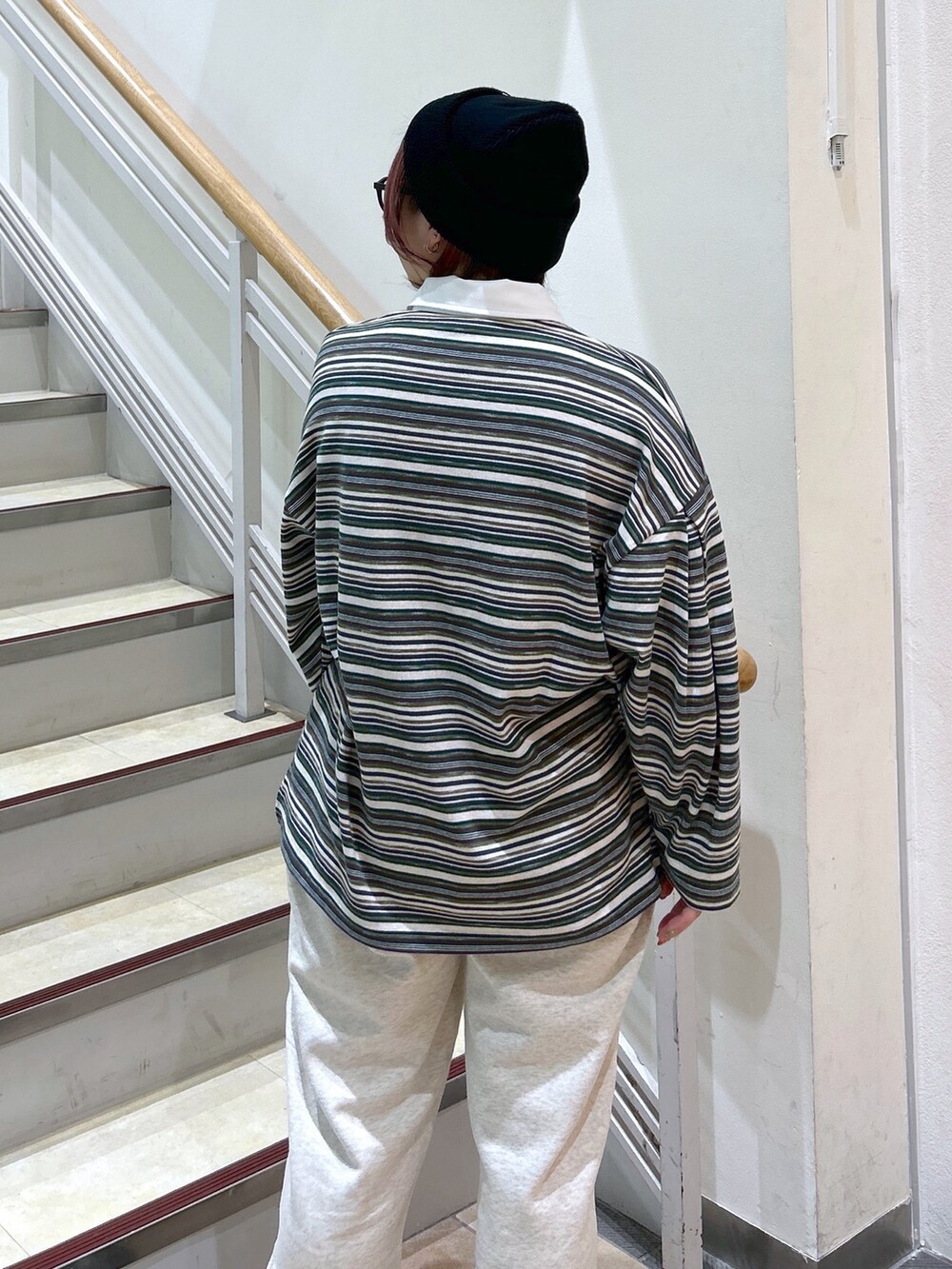 グリーン系のポロシャツ、ベージュ系のスウェットパンツ、グリーン系のバックパック/リュックを着用したレディースの冬コーディネートの9枚目の写真