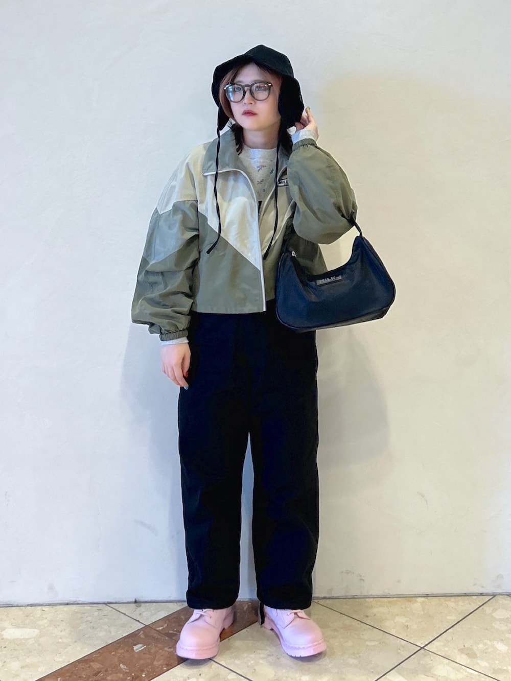 グレー系のTシャツ/カットソー、ベージュ系のナイロンジャケット、ブラック系のサロペット/オーバーオールを着用したレディースの春コーディネートの3枚目の写真