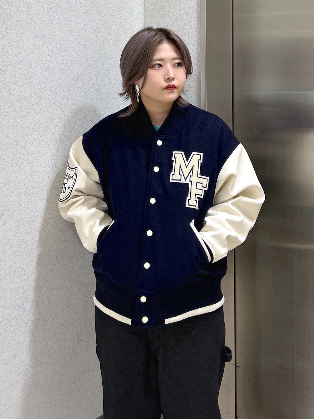 ブルー系のスタジャン、ブラック系のサロペット/オーバーオール、ベージュ系のスニーカーを着用したレディースの秋コーディネートの5枚目の写真