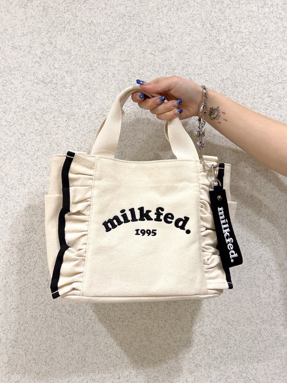 グレー系のTシャツ/カットソー、ブラック系のスカート、ホワイト系のショルダーバッグを着用したレディースの夏コーディネートの5枚目の写真