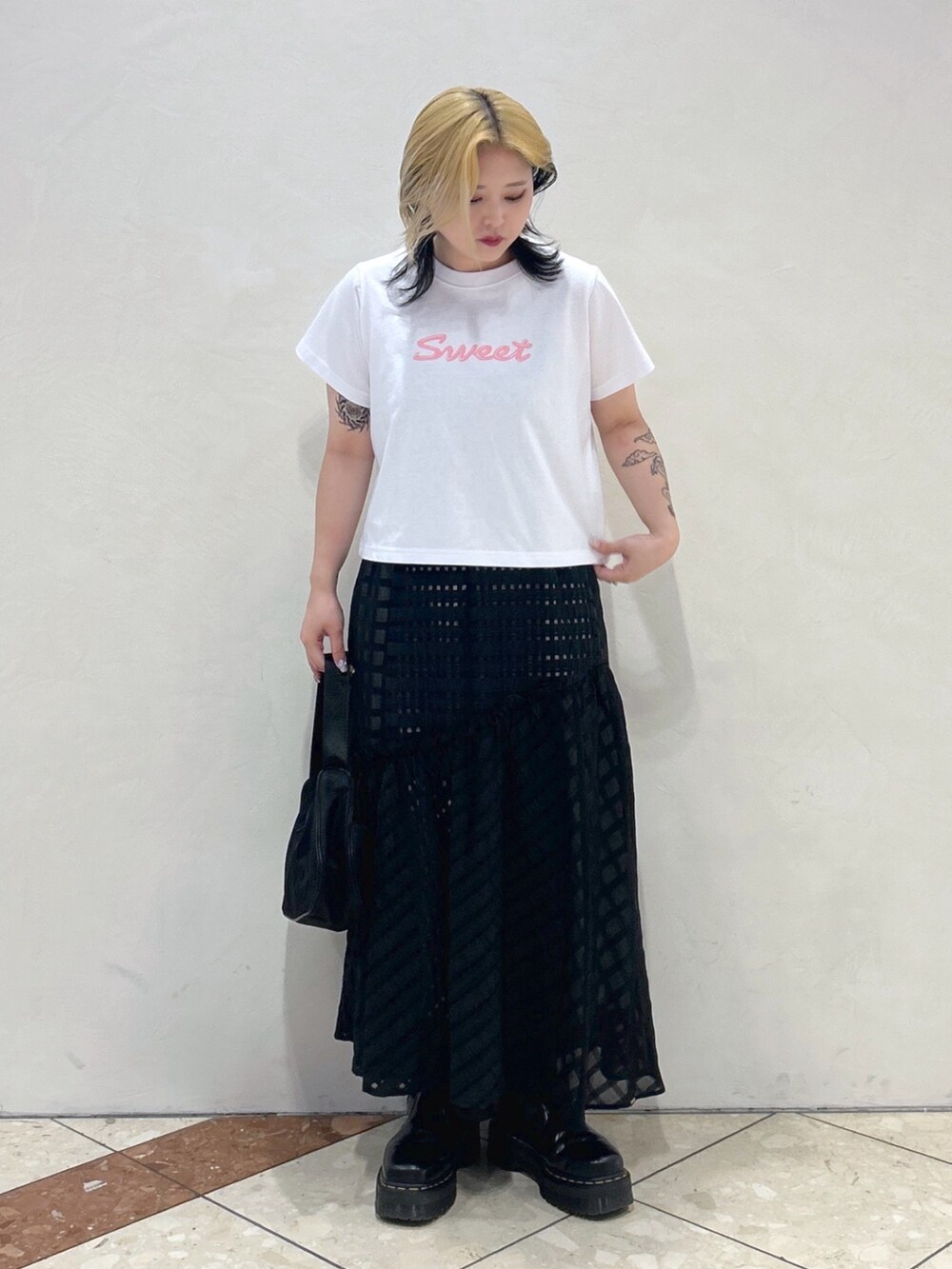 ピンク系のTシャツ/カットソー、ブラック系のスカート、ブラック系のハンドバッグを着用したレディースの春コーディネートの2枚目の写真