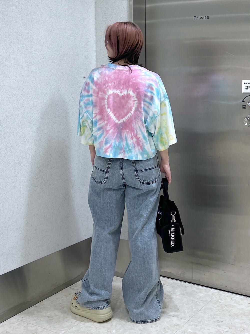 ブルー系のデニムパンツ、ブラック系のショルダーバッグ、ベージュ系のサンダルを着用したレディースの夏コーディネートの3枚目の写真