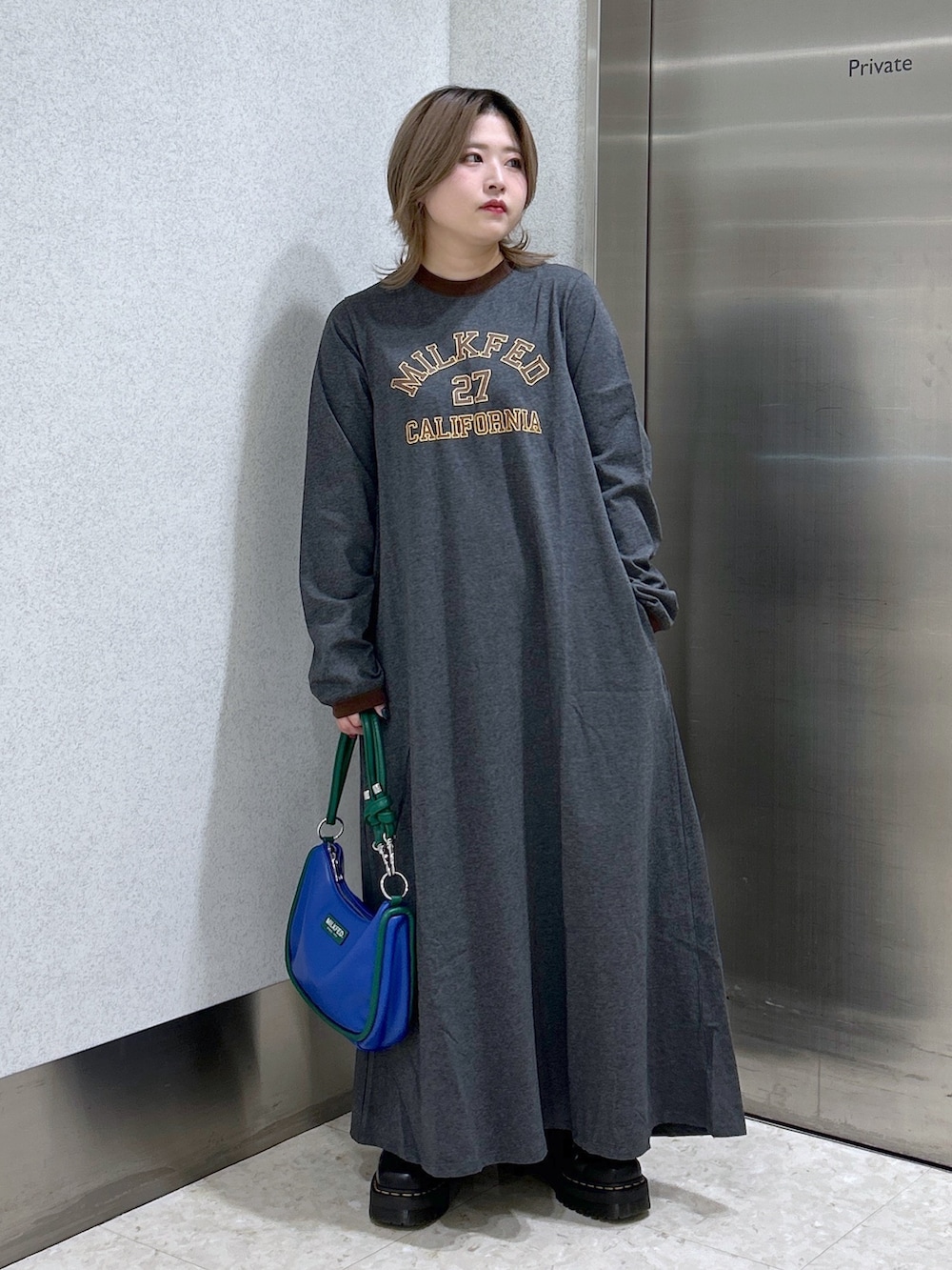 グレー系のワンピース、グリーン系のMA-1、シルバー系のショルダーバッグを着用したレディースの冬コーディネートの4枚目の写真