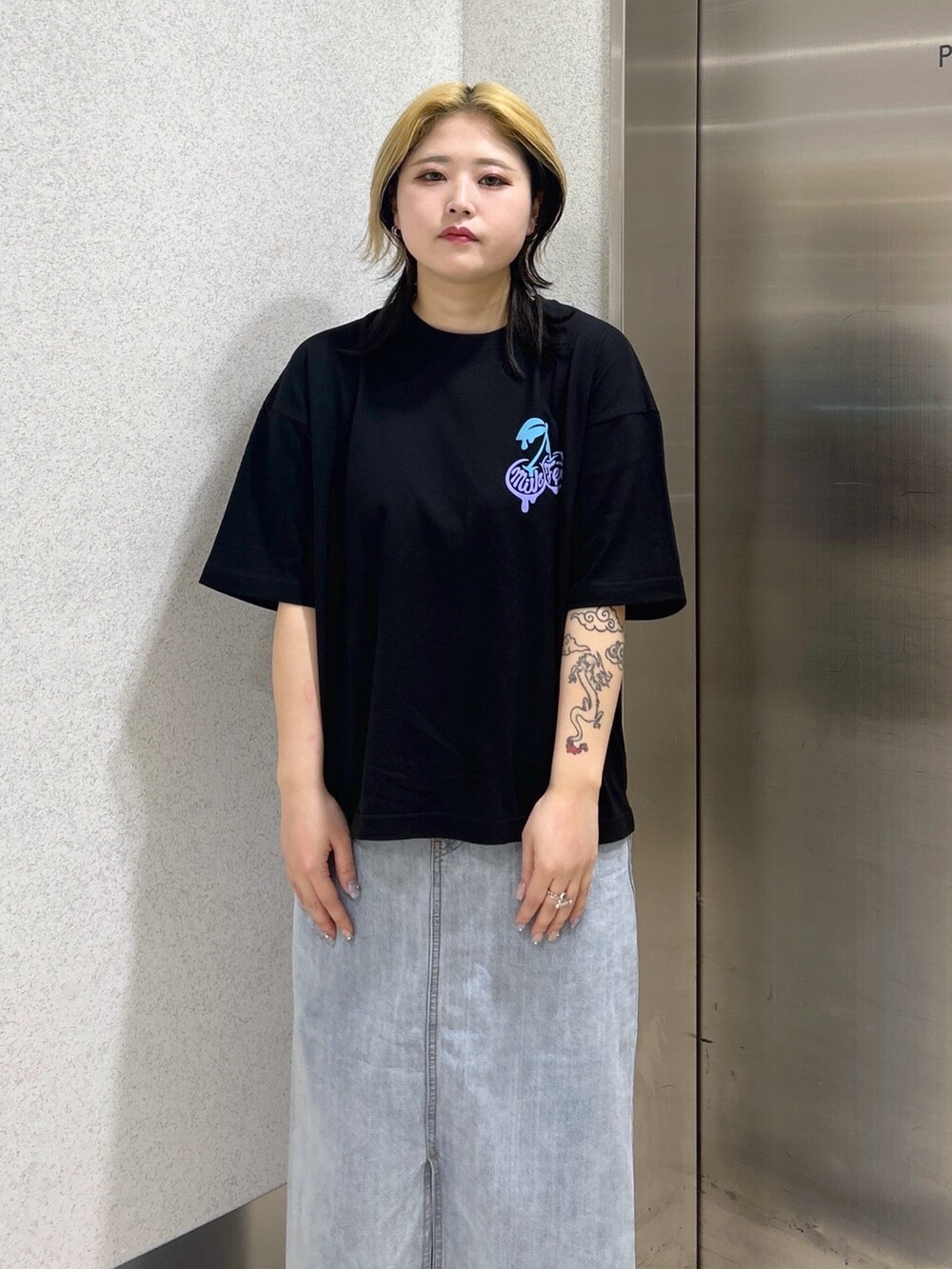 ブラック系のTシャツ/カットソー、ブルー系のデニムスカート、ブルー系のハンドバッグを着用したレディースの春コーディネートの3枚目の写真