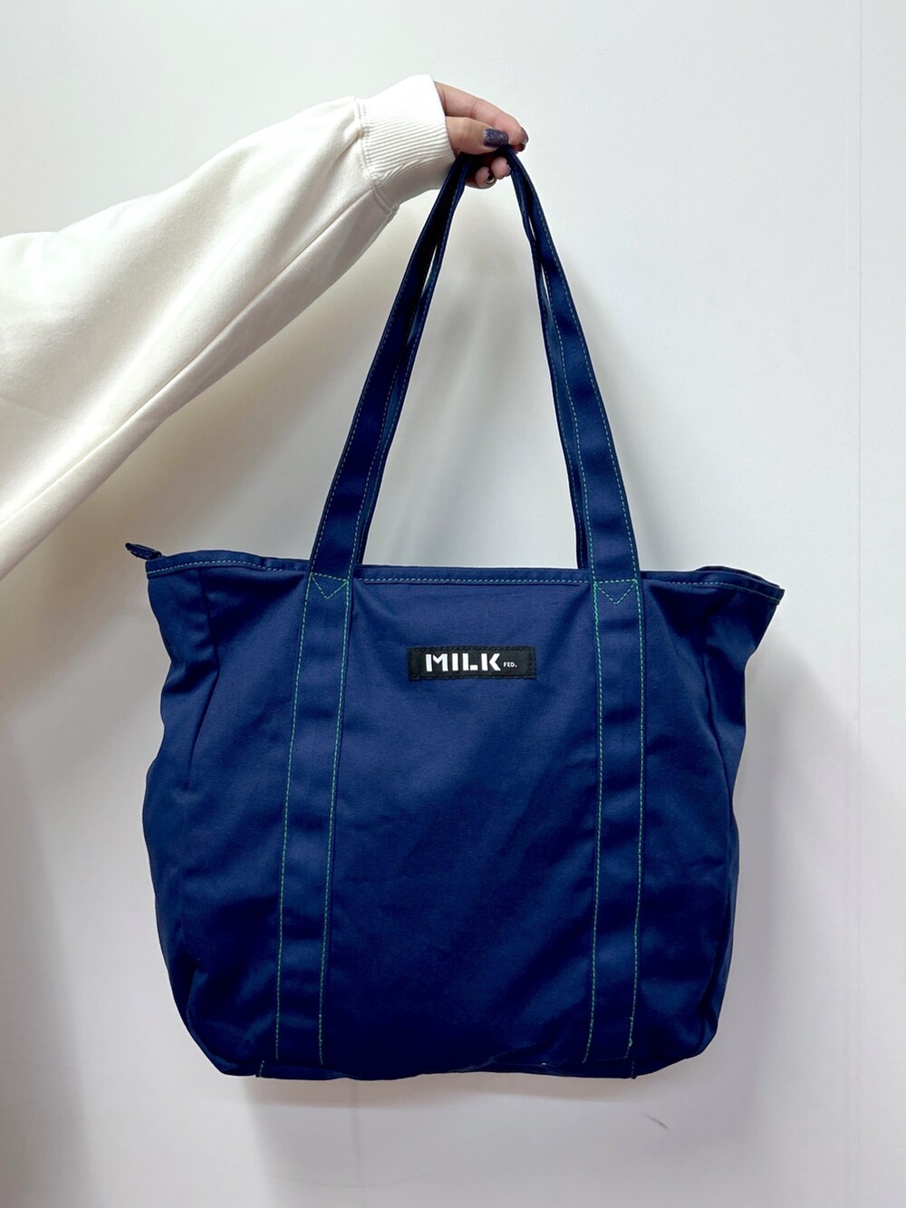 ホワイト系のスウェット、ブルー系のトートバッグ、ブルー系のデニムパンツを着用したレディースの秋コーディネートの5枚目の写真