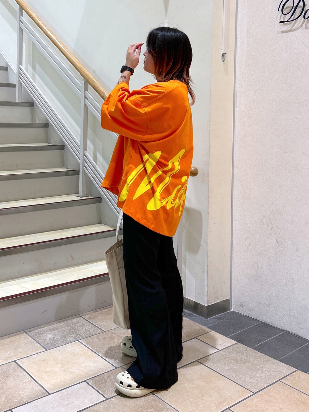 オレンジ系のTシャツ/カットソー、ブラック系のその他パンツ、ブラック系のトートバッグを着用したレディースの夏コーディネートの3枚目の写真