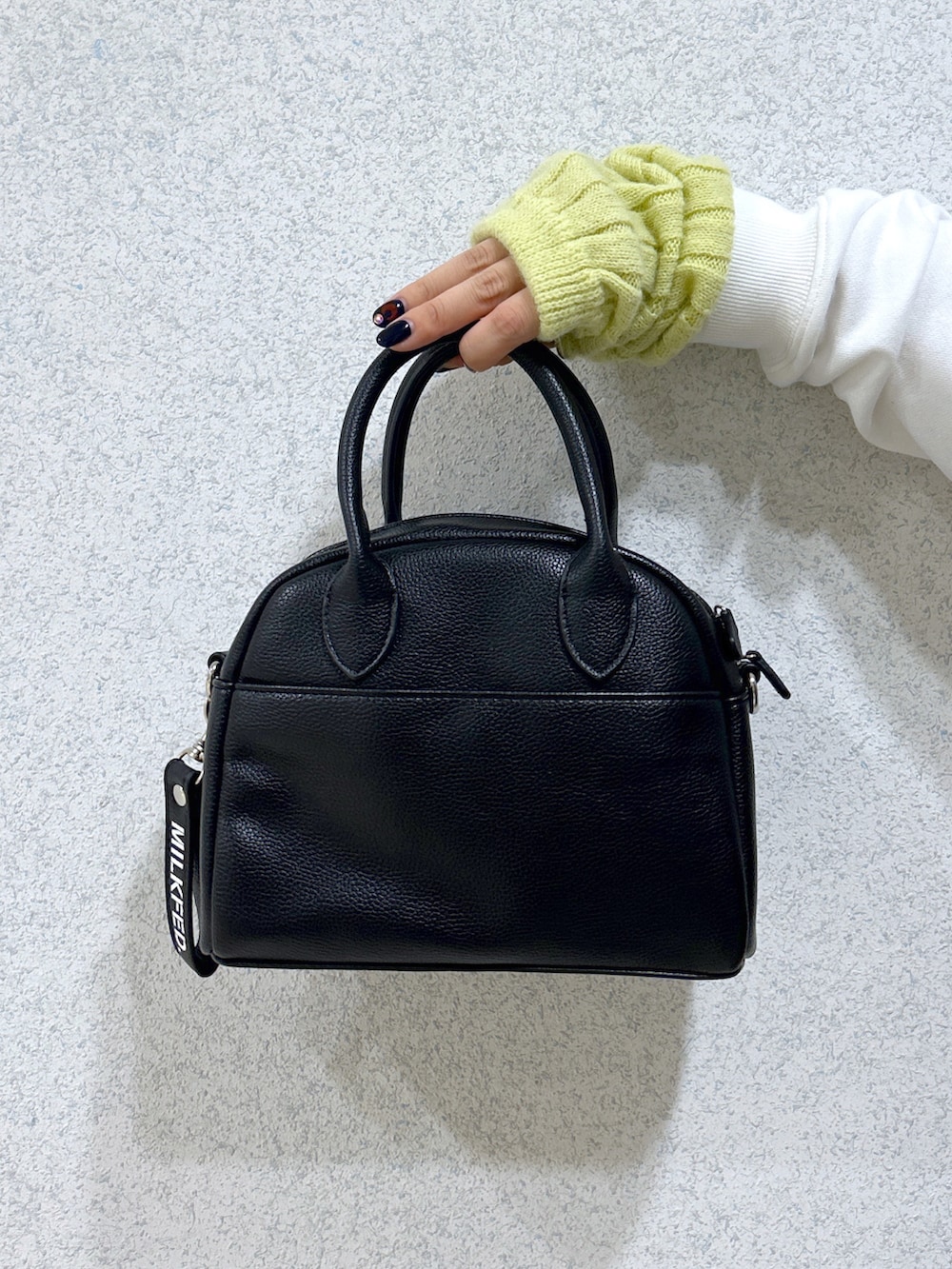 ブラック系のベスト、ホワイト系のスウェット、ブラック系のボストンバッグを着用したレディースの秋コーディネートの5枚目の写真