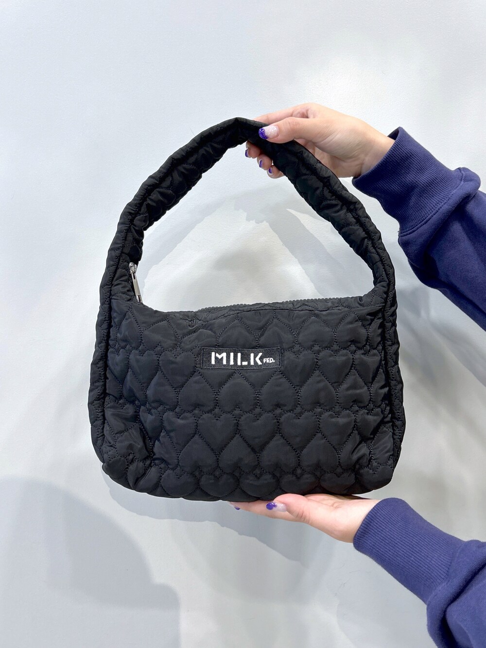 ブラック系のベスト、ブルー系のスウェット、ブラック系のスカートを着用したレディースの秋コーディネートの5枚目の写真