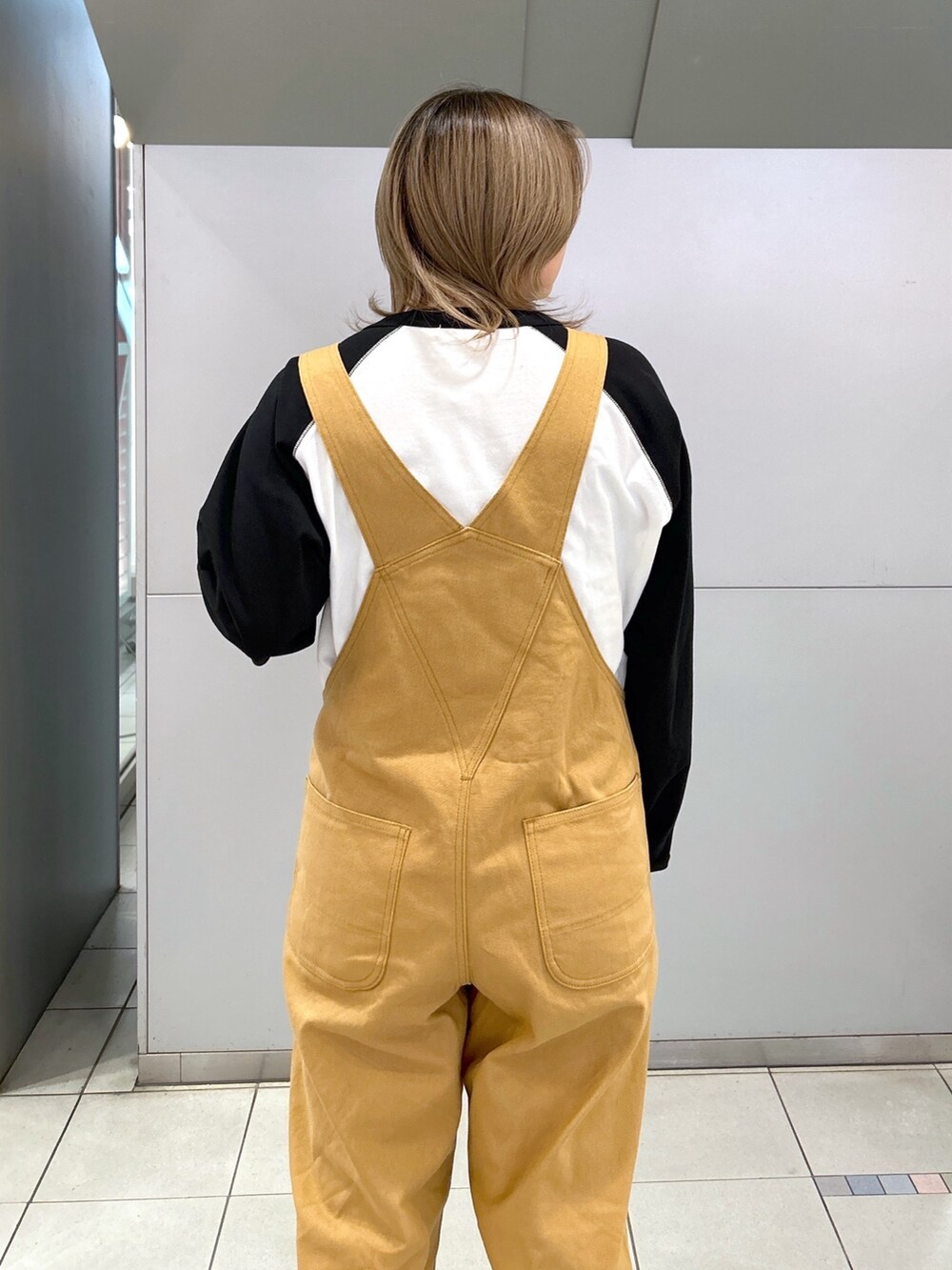 ブラック系のTシャツ/カットソー、ベージュ系のサロペット/オーバーオール、ブラック系のブーツを着用したレディースの冬コーディネートの6枚目の写真