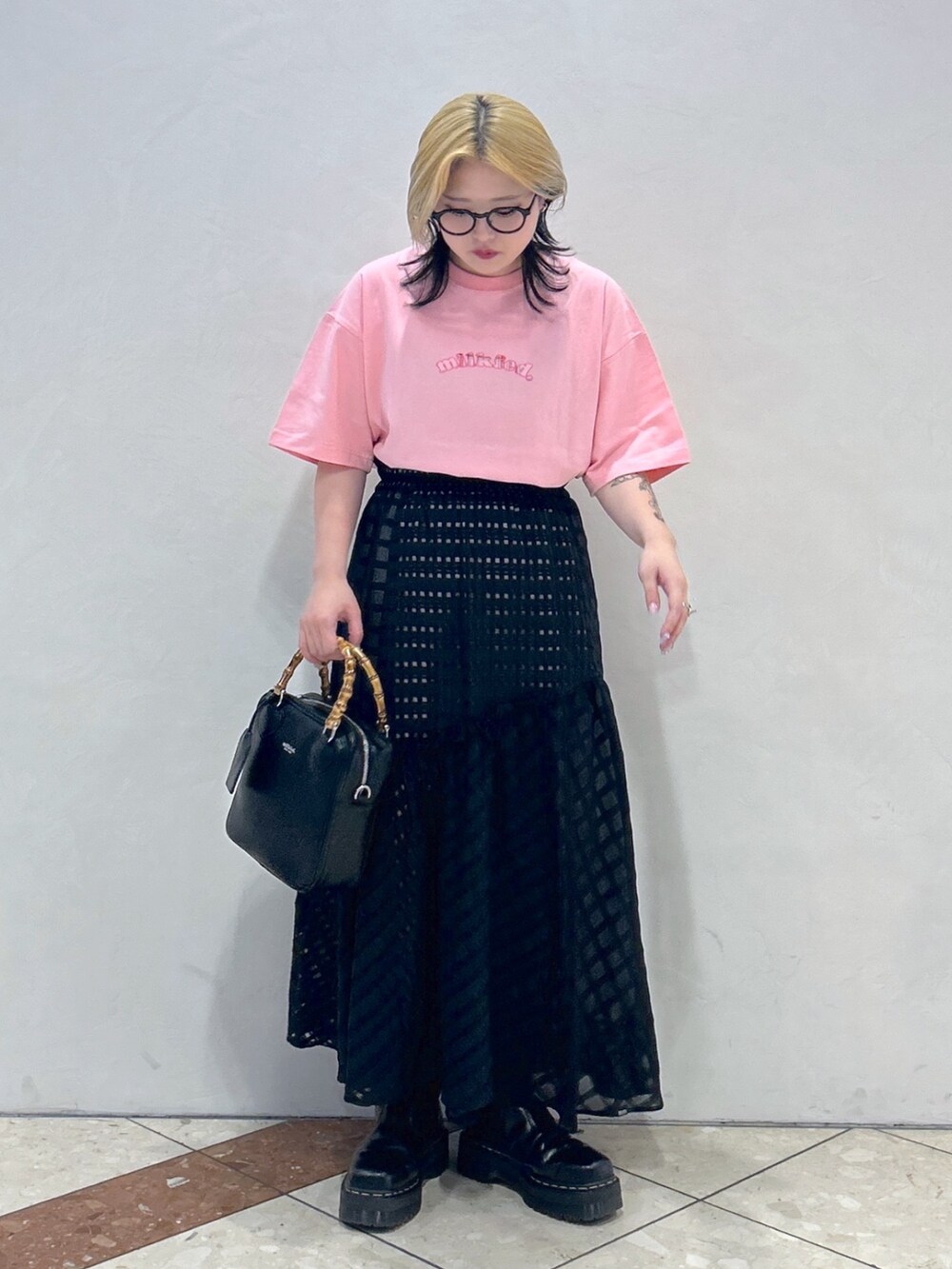 ブラック系のブーツ、ブラック系のスカート、ブラック系のショルダーバッグを着用したレディースの春コーディネートの2枚目の写真