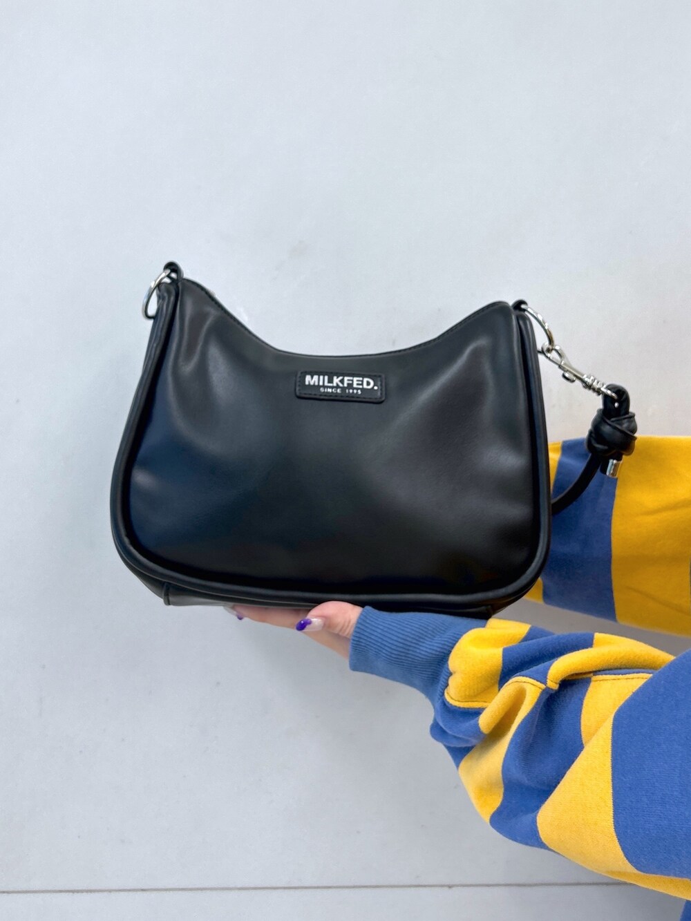 イエロー系のスウェット、ブラック系のデニムパンツ、ブラック系のショルダーバッグを着用したレディースの冬コーディネートの5枚目の写真