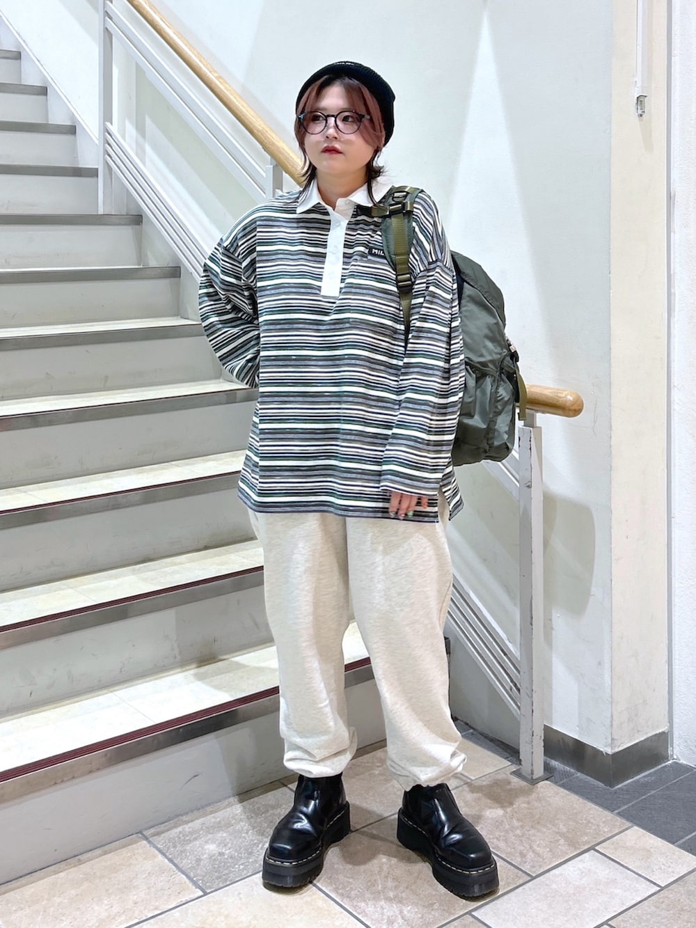 グリーン系のポロシャツ、ベージュ系のスウェットパンツ、グリーン系のバックパック/リュックを着用したレディースの冬コーディネートの3枚目の写真