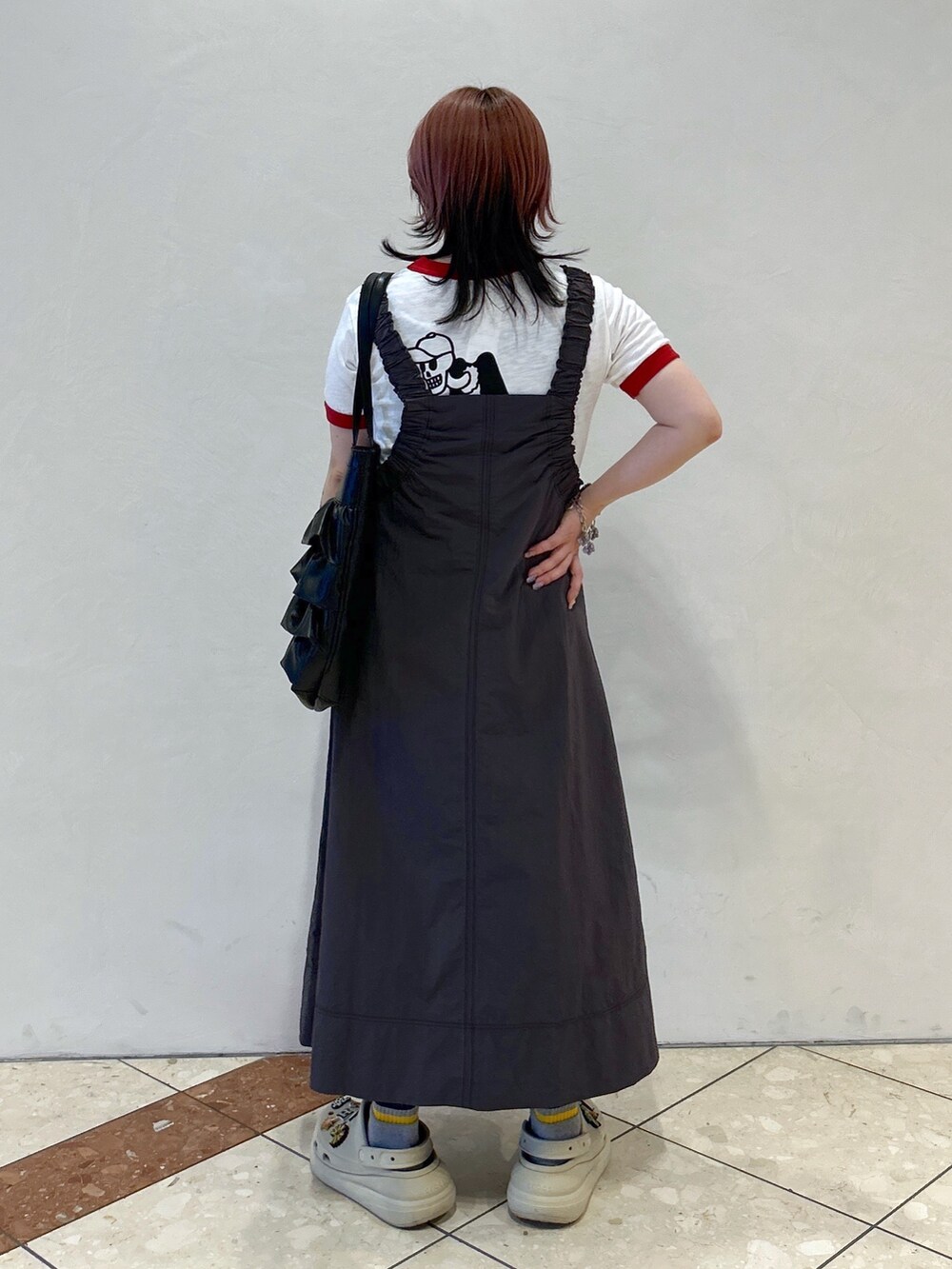 レッド系のTシャツ/カットソー、ベージュ系のサンダル、ブラック系のトートバッグを着用したレディースの春コーディネートの4枚目の写真